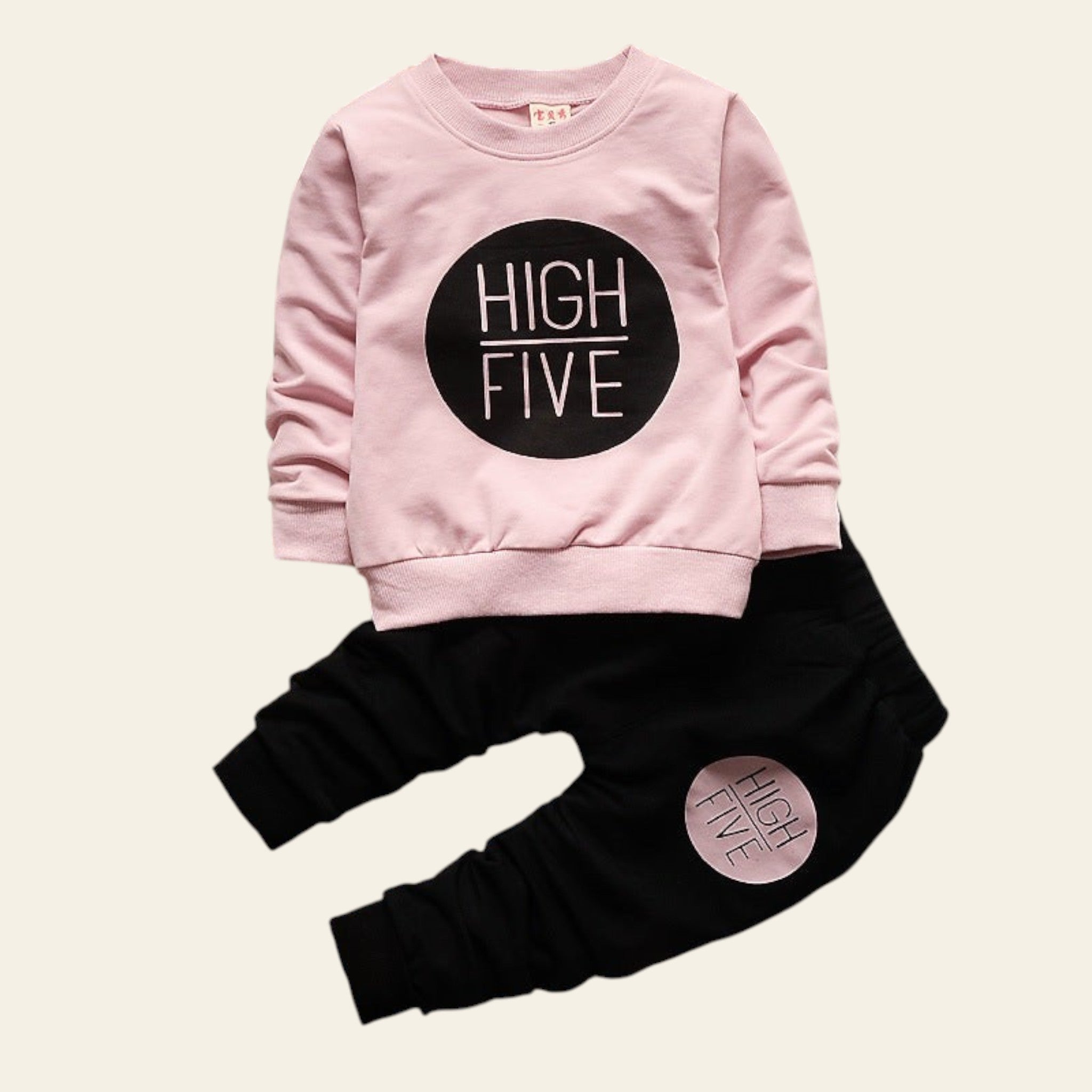 Pink sweatshirt and black pants set with 'HIGH FIVE' text on a wooden surface.