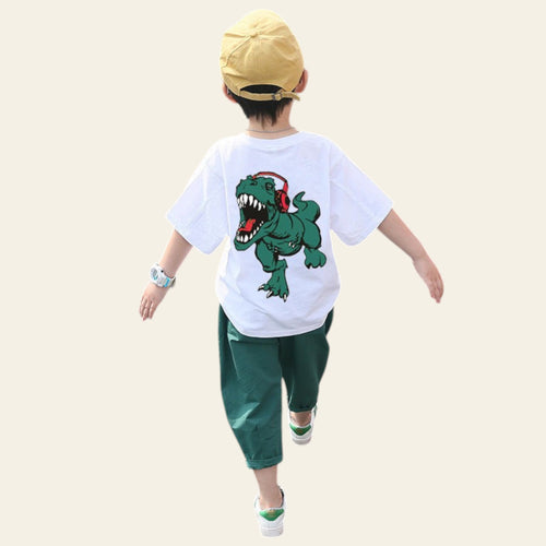 Child wearing a white t-shirt with a dinosaur graphic, green pants, and a yellow cap on a crosswalk.