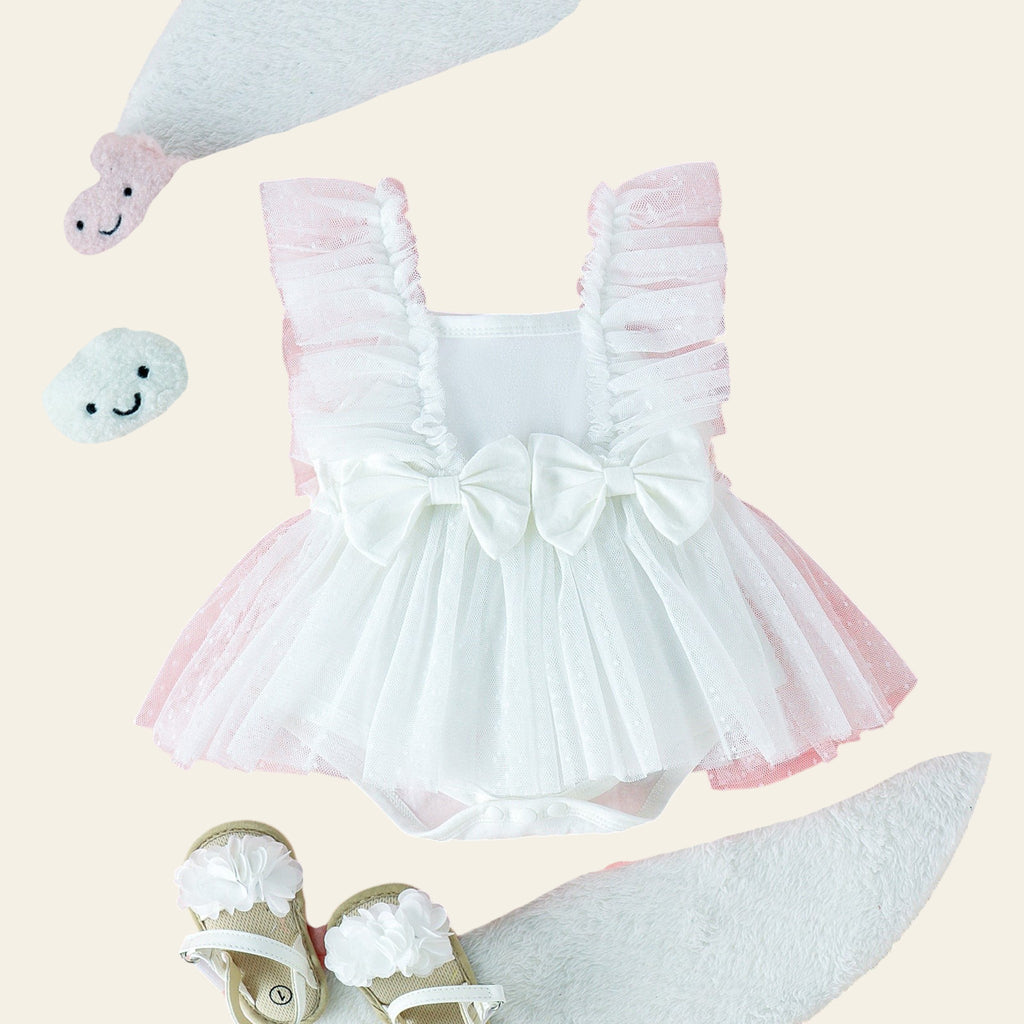 White baby dress with ruffles, shoes, and plush toys on a pink fabric background