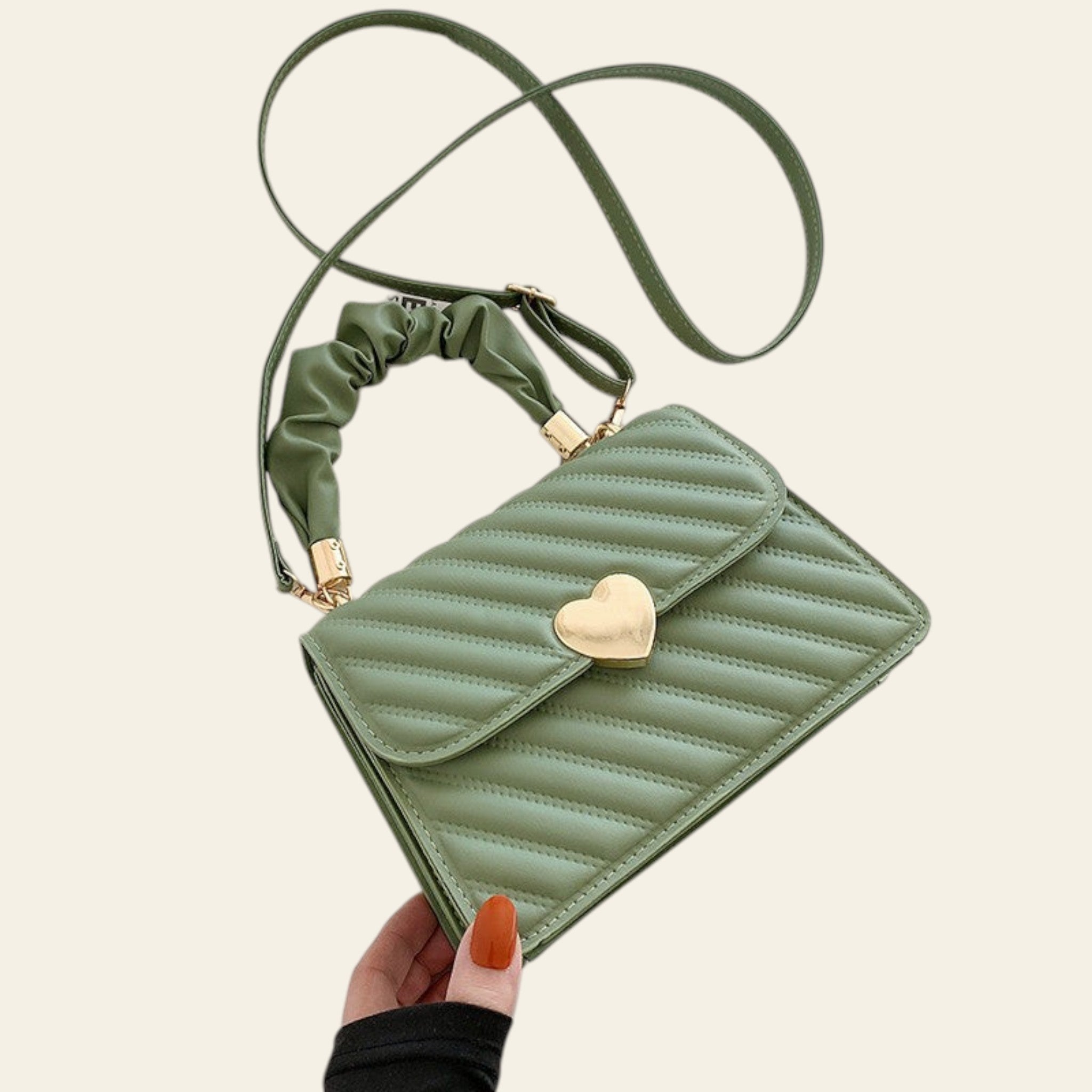 Green quilted handbag with a heart-shaped clasp on a light background