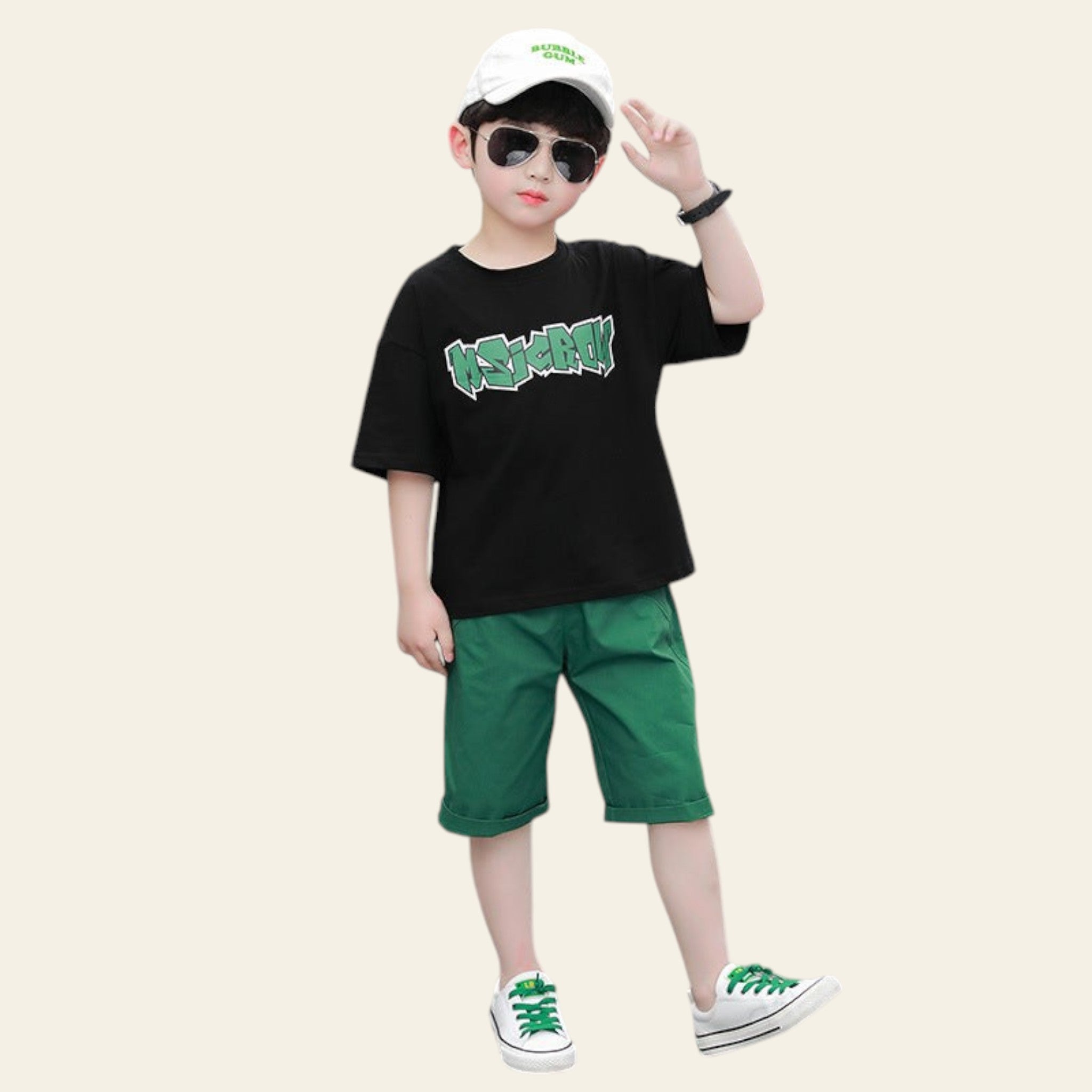 Child wearing a black t-shirt with green text, green shorts, and white sneakers on a street.