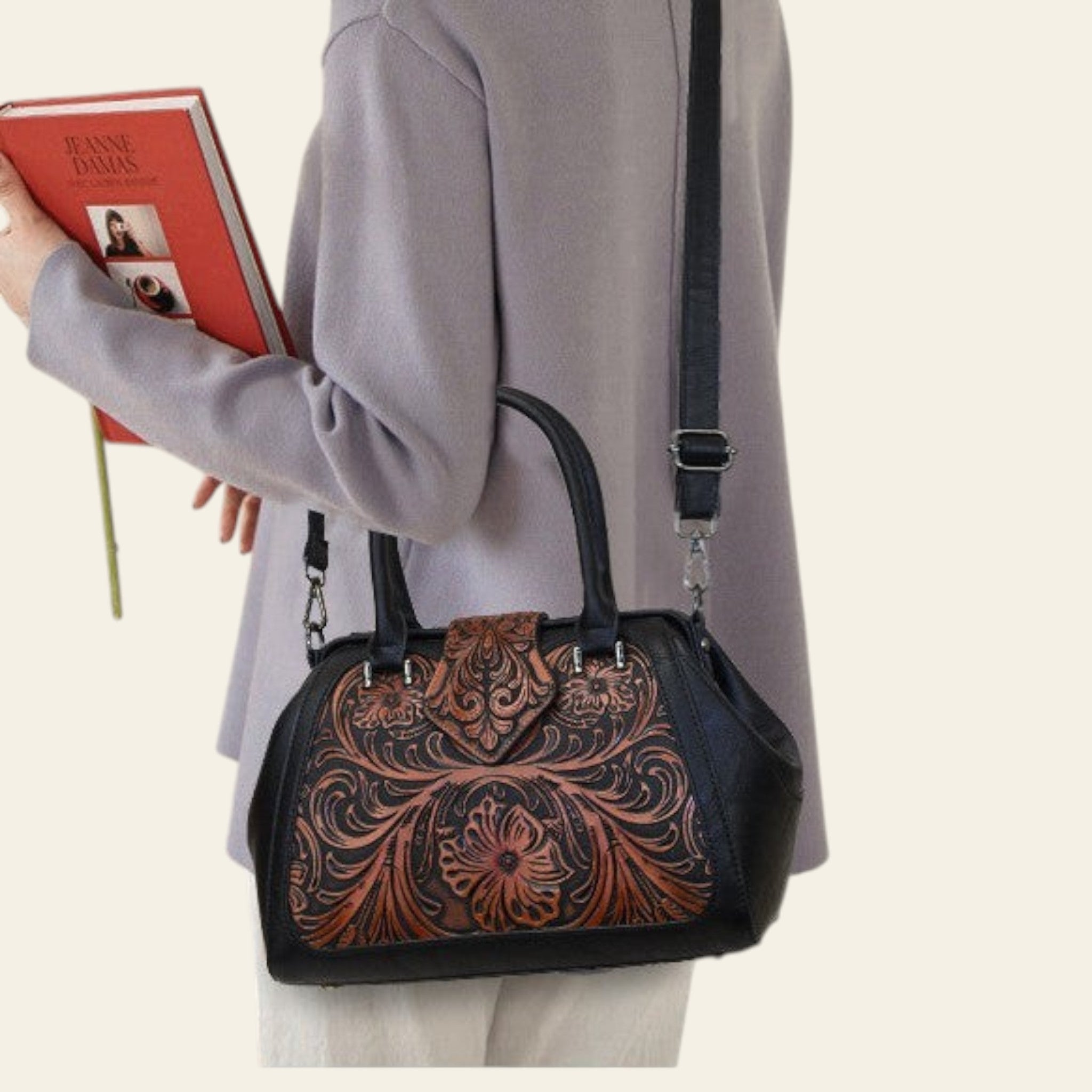 Person holding a book with a decorative handbag on a neutral background