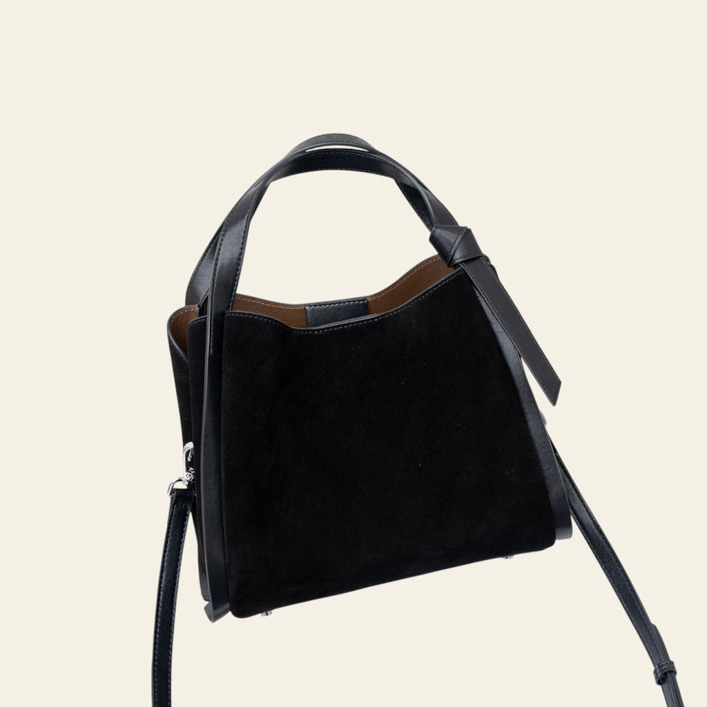 Black handbag on a white surface with a blurred background