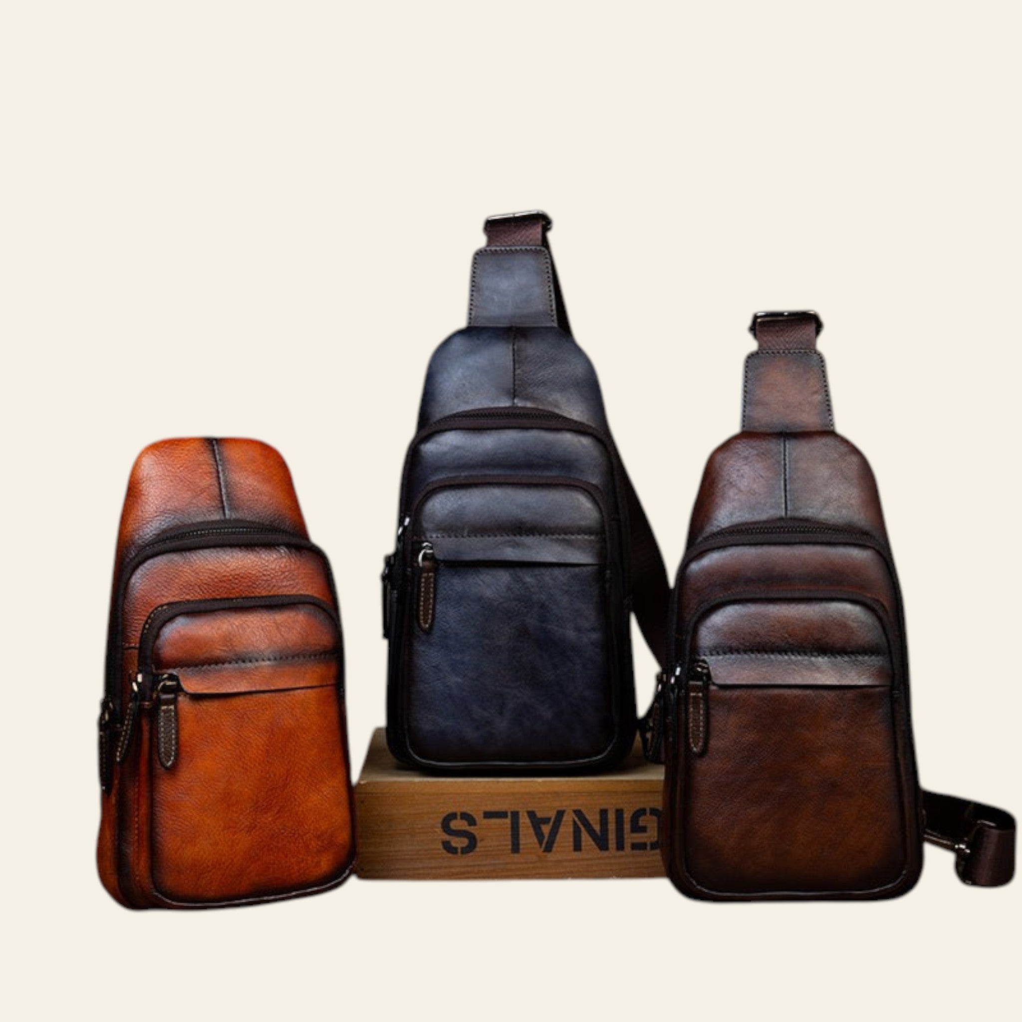 Three leather sling bags on a wooden surface with a rustic background