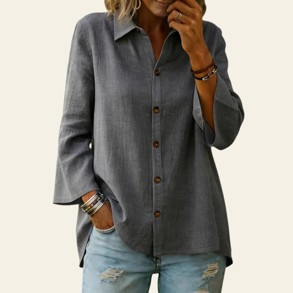 Person wearing a gray button-up shirt and light blue jeans with a blurred background