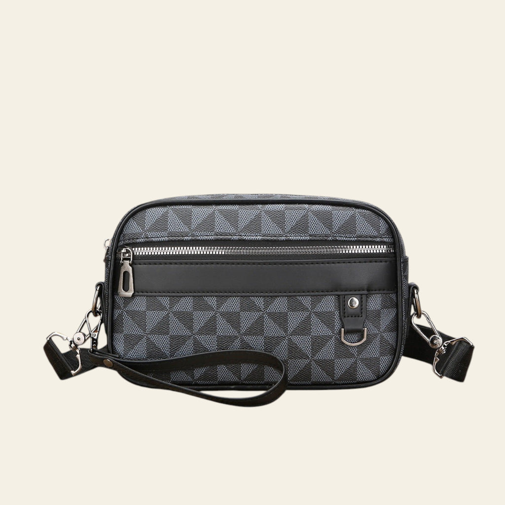 Black patterned crossbody bag on a wooden surface with a white background