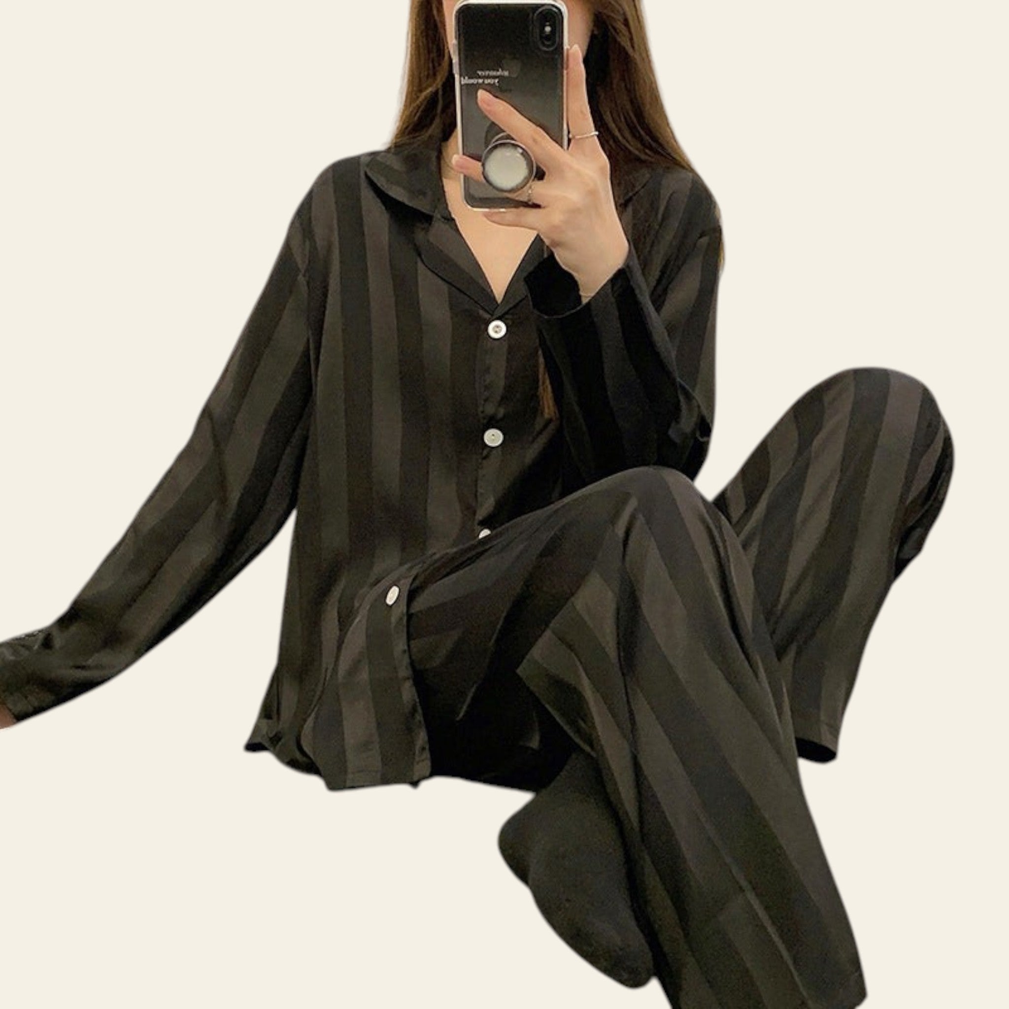 Person wearing a black striped pajama set sitting on a bed.