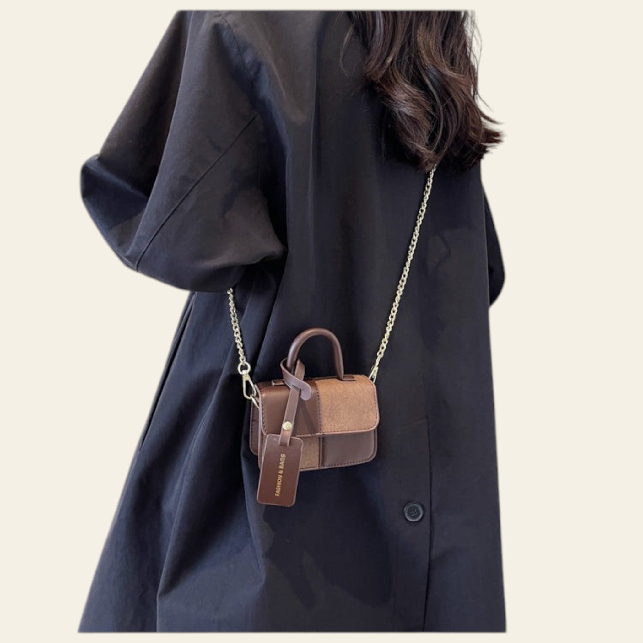 Person wearing a black coat with a brown handbag on a plain background