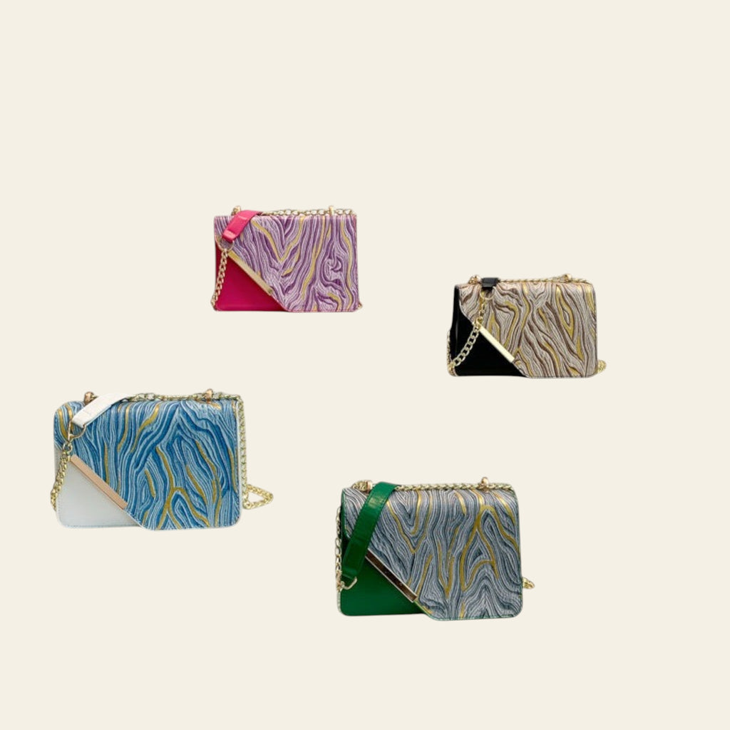 Colorful handbags on display stands with a lamp and framed picture in the background.