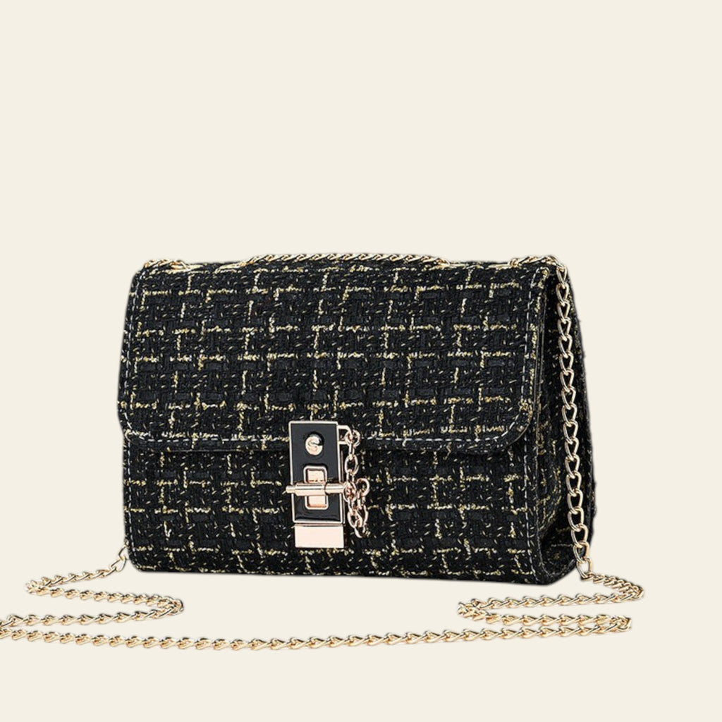 Black textured handbag with gold chain strap on a light gray background