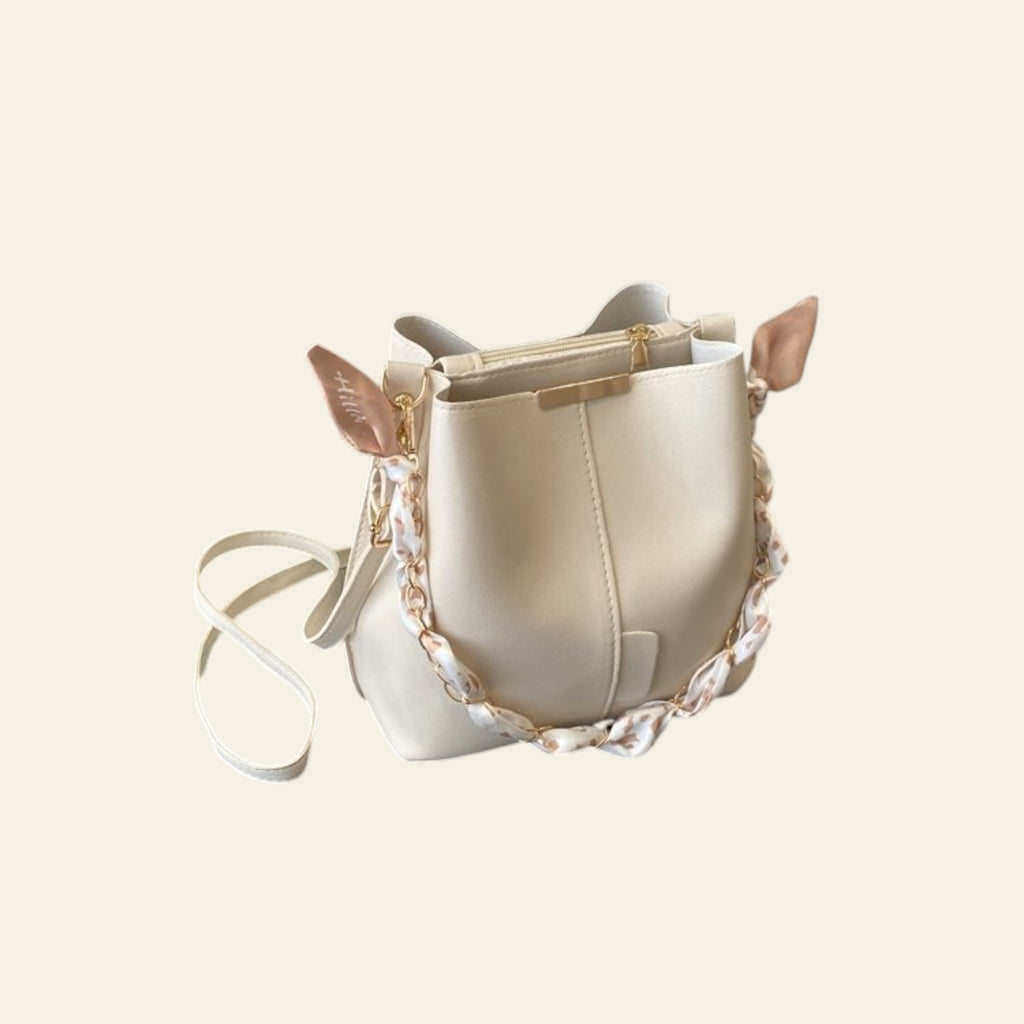 White handbag with gold accents on a desk next to a laptop