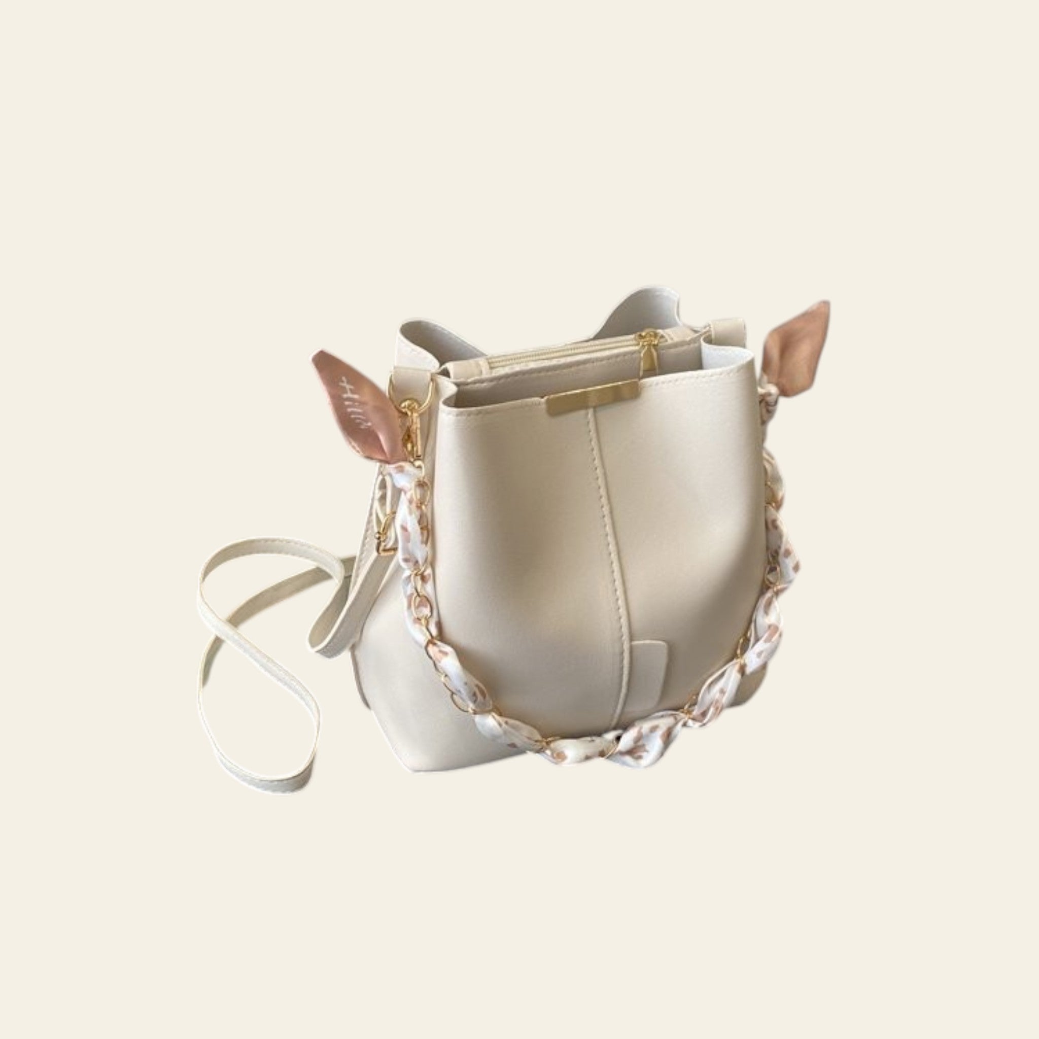 White handbag with gold accents on a desk next to a laptop