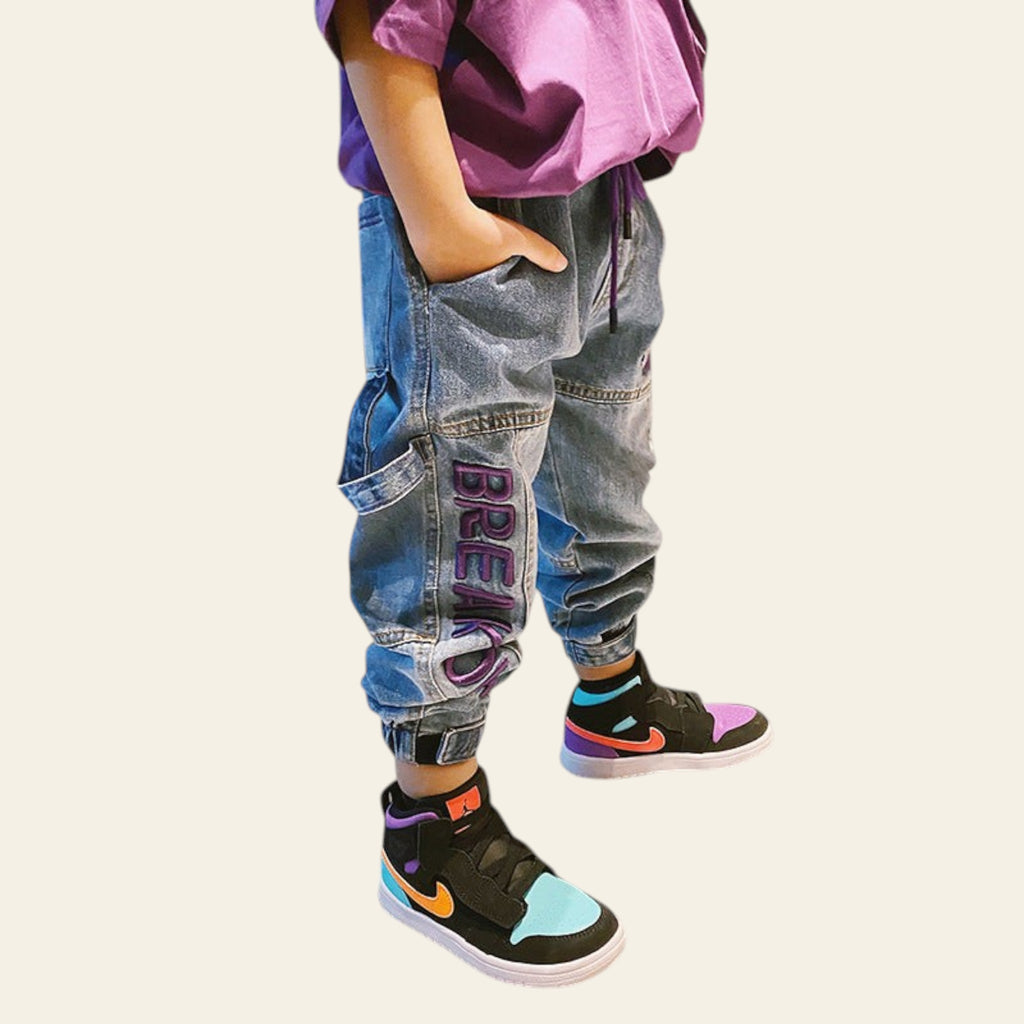 Person wearing colorful sneakers and patchwork jeans in a modern living room.