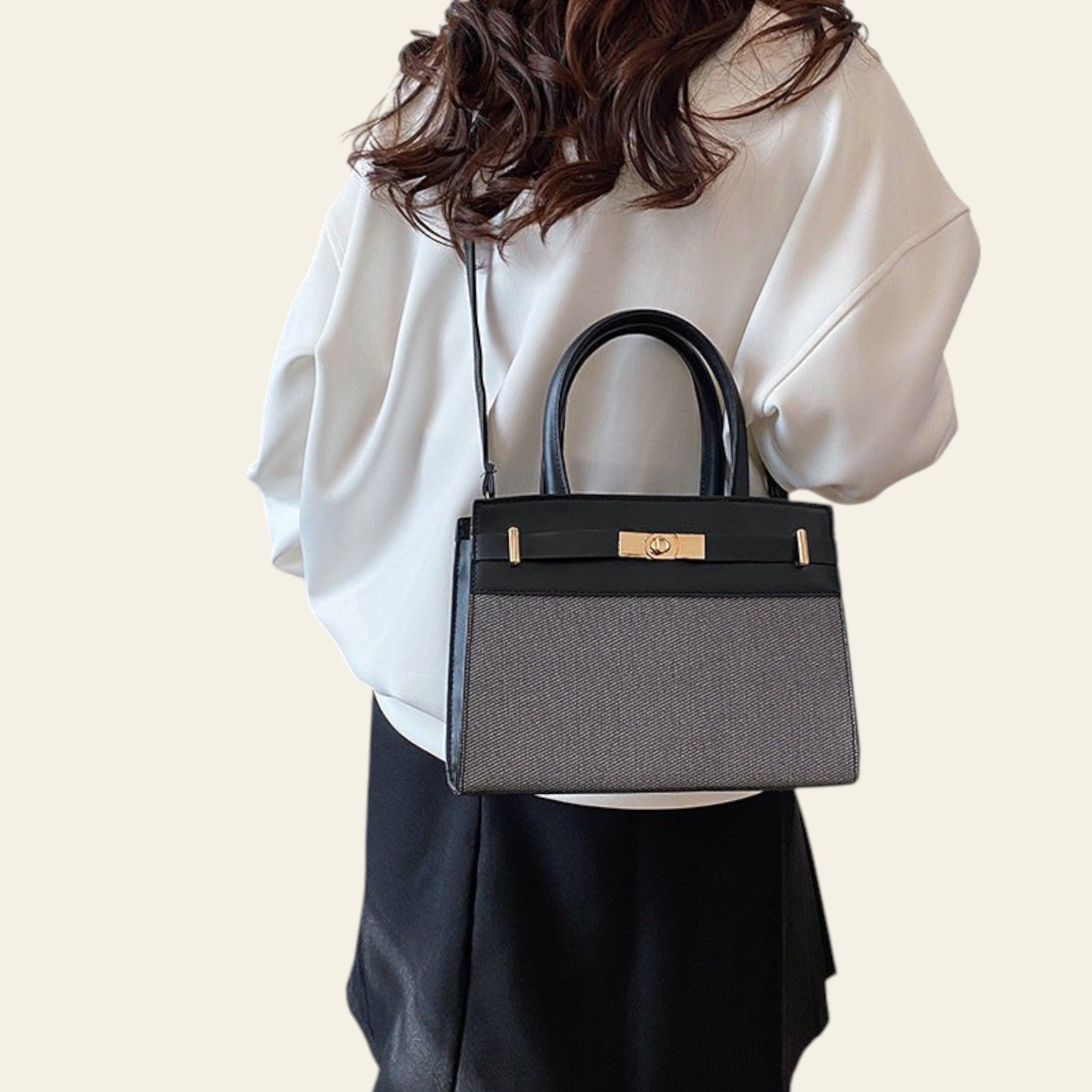 Person holding a black and gray handbag in an indoor setting