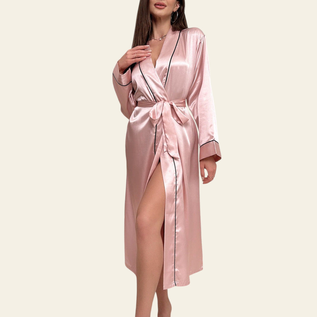 Woman wearing a pink satin robe in a stylish room with decor elements.