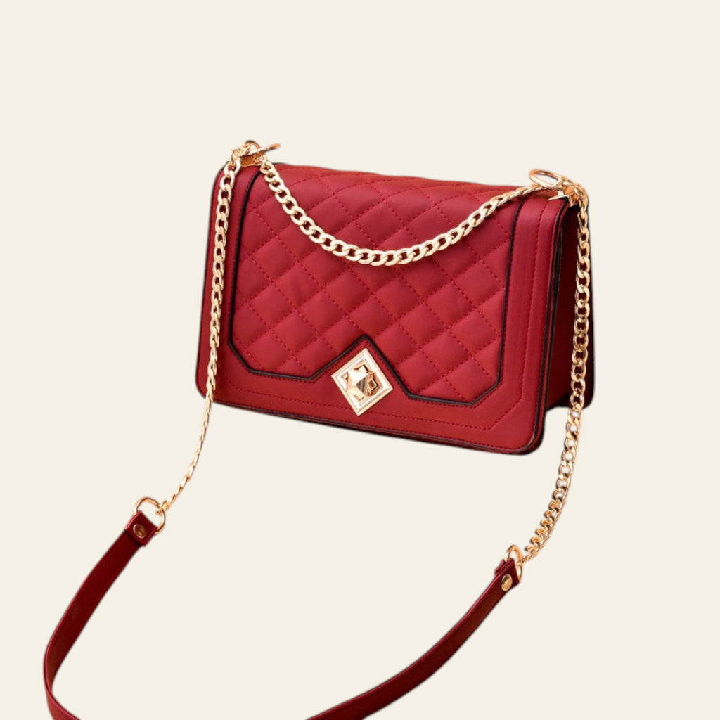 Red quilted handbag with gold chain strap on a beige background