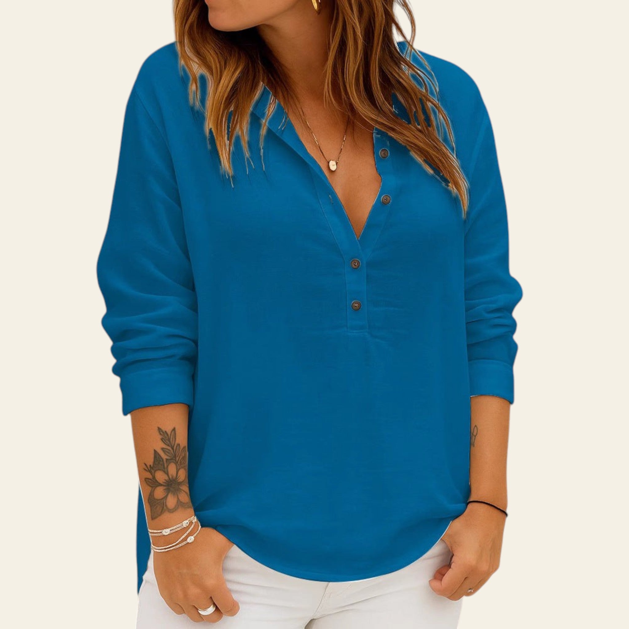 Woman wearing a blue long-sleeve shirt against a brick wall.