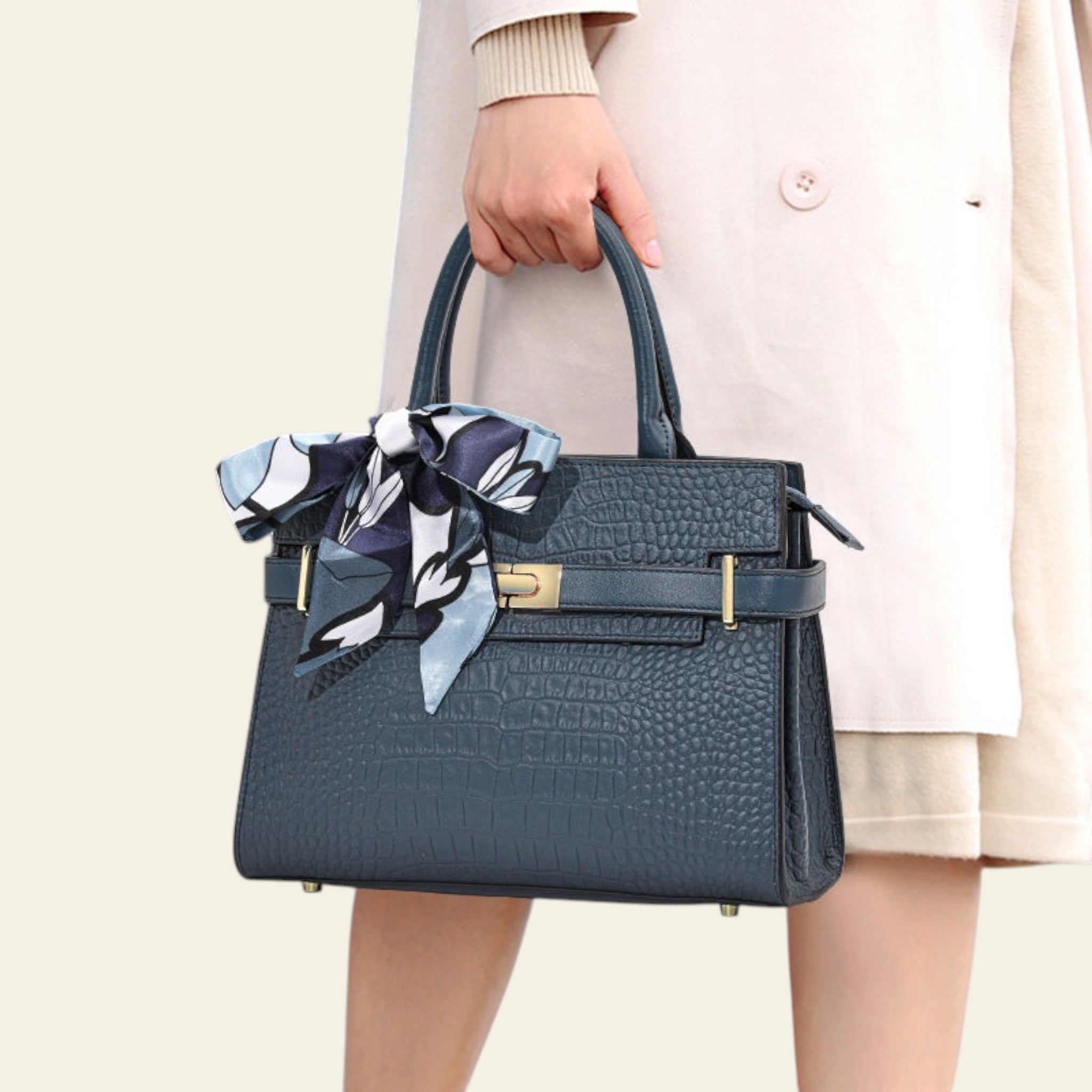 Blue handbag with a decorative bow held by a person wearing a beige coat.