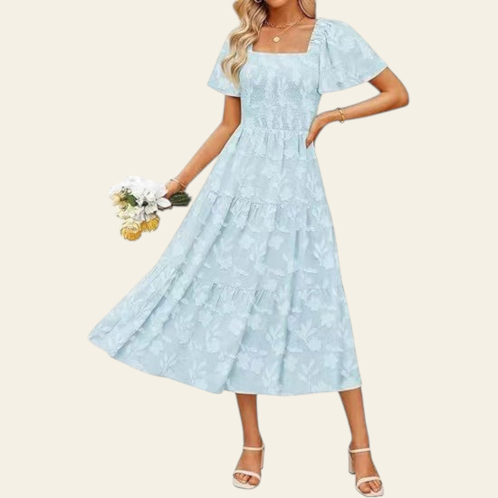 Woman wearing a light blue lace dress holding flowers on a white background