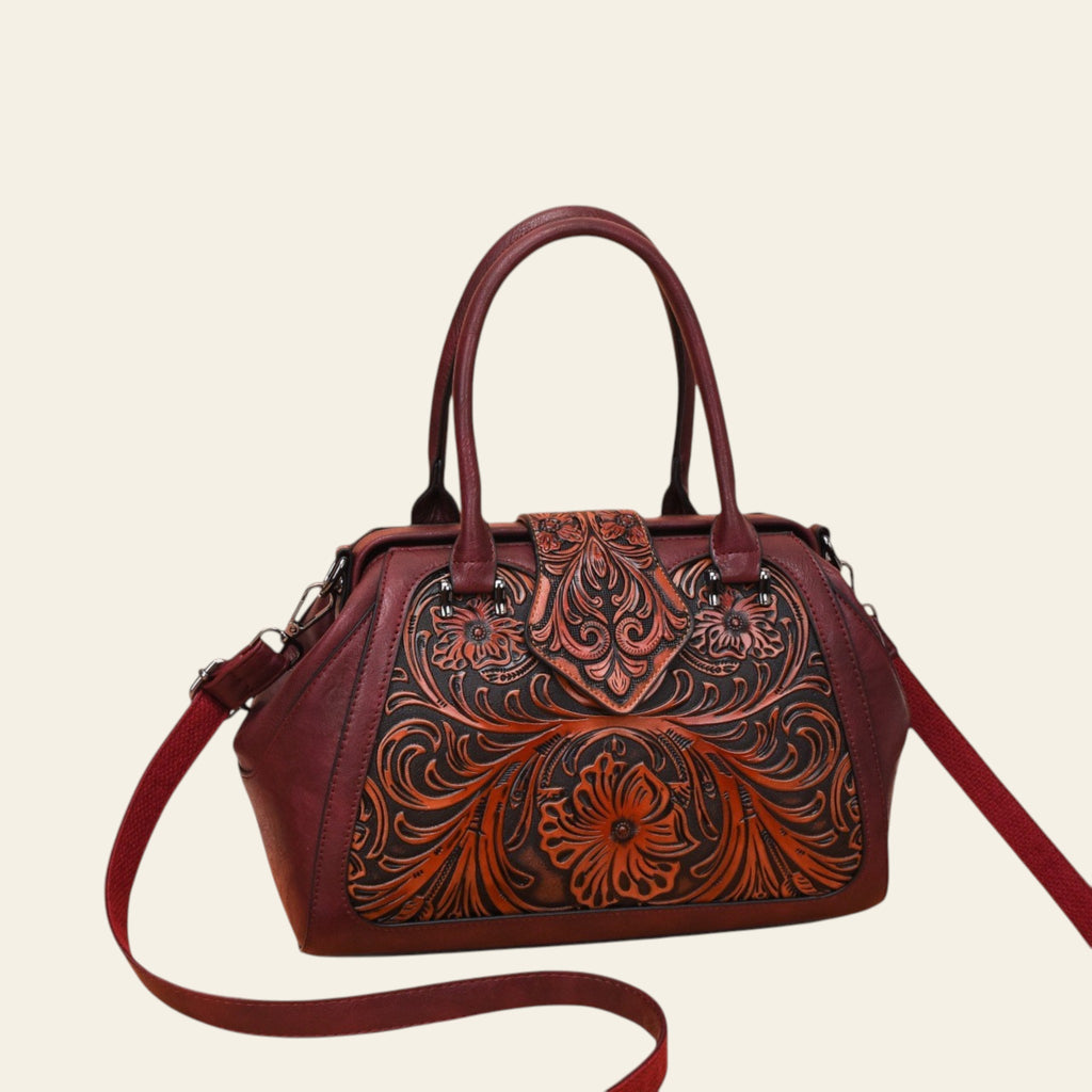 Brown leather handbag with intricate floral patterns on a white background