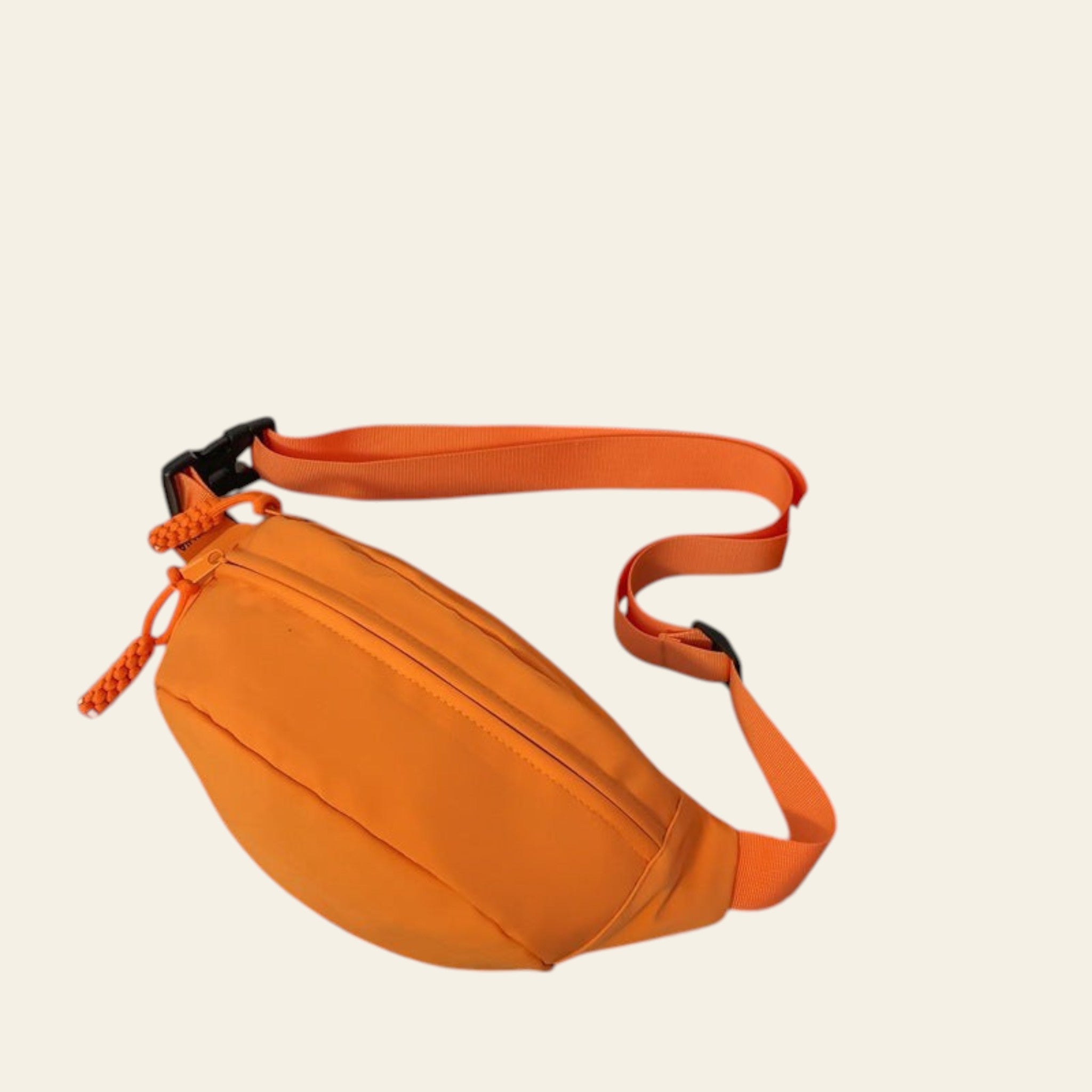 Orange waist bag on a glass surface with a book and snack packet in the background