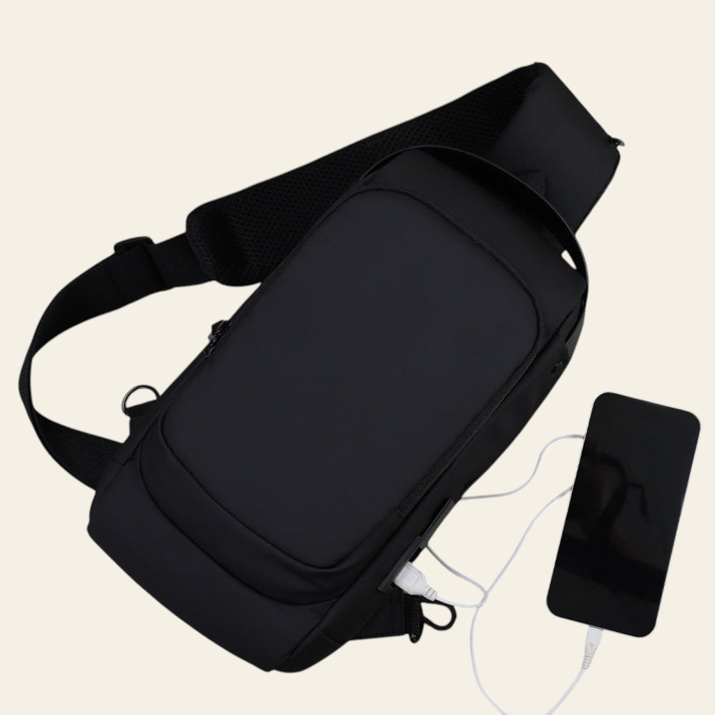 Black shoulder bag with a phone and cable on a gray surface