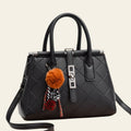Black quilted handbag with colorful pom-pom keychain on a white background