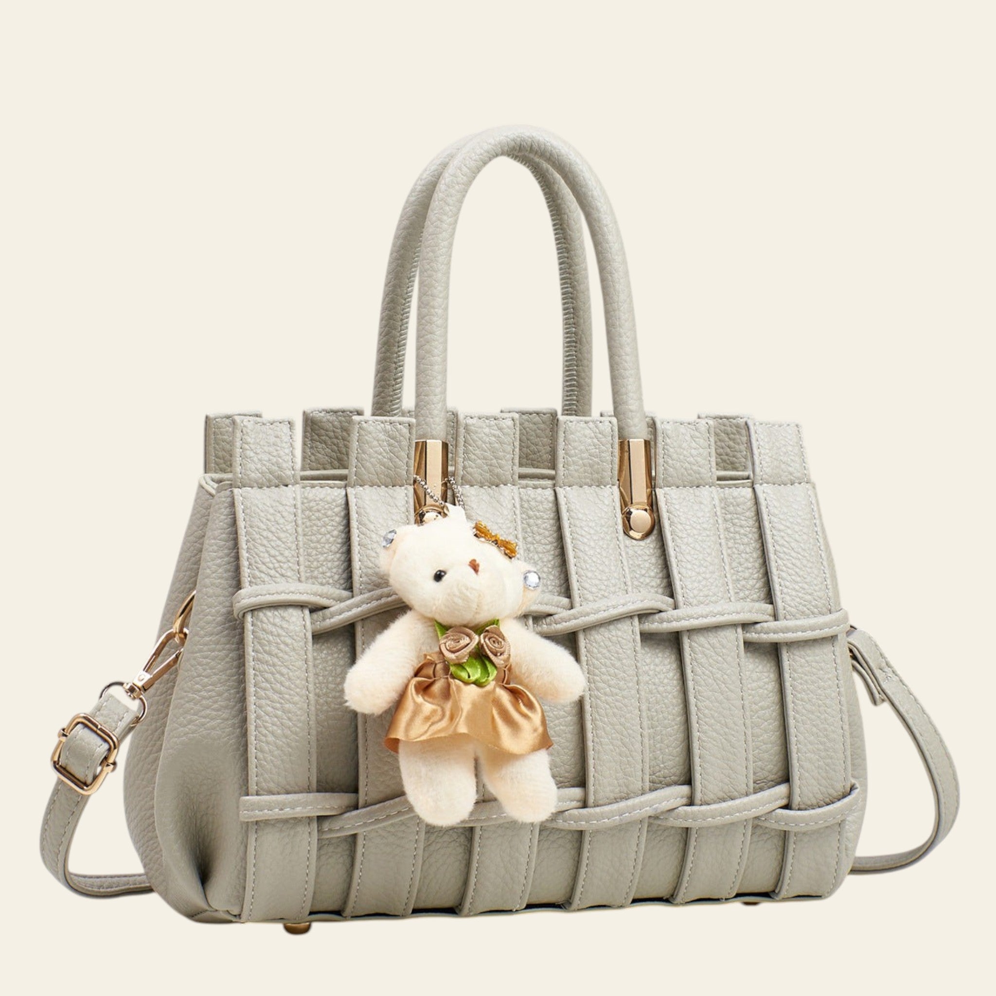 Gray woven handbag with a teddy bear keychain on a light gray background