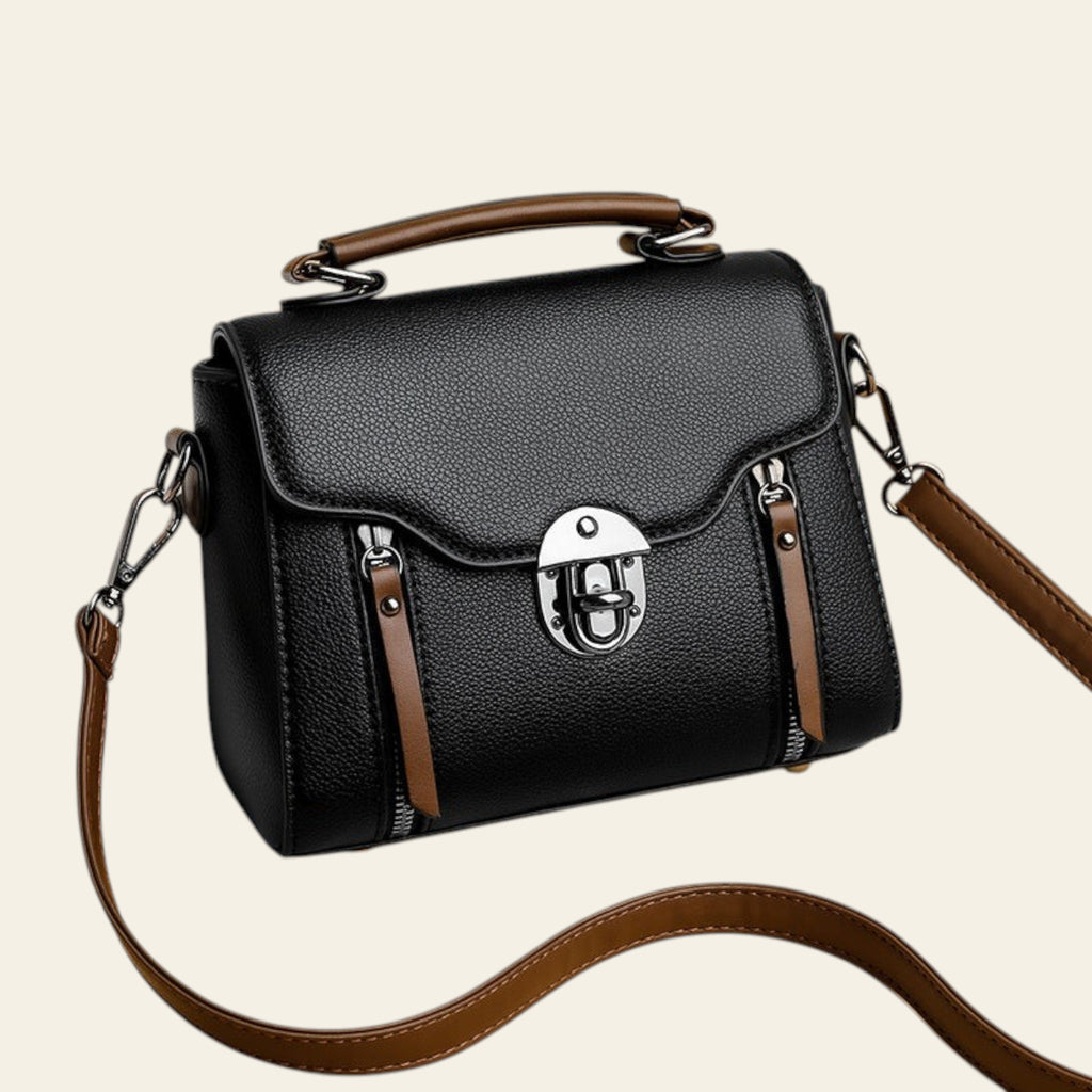 Black handbag with brown accents on a beige background