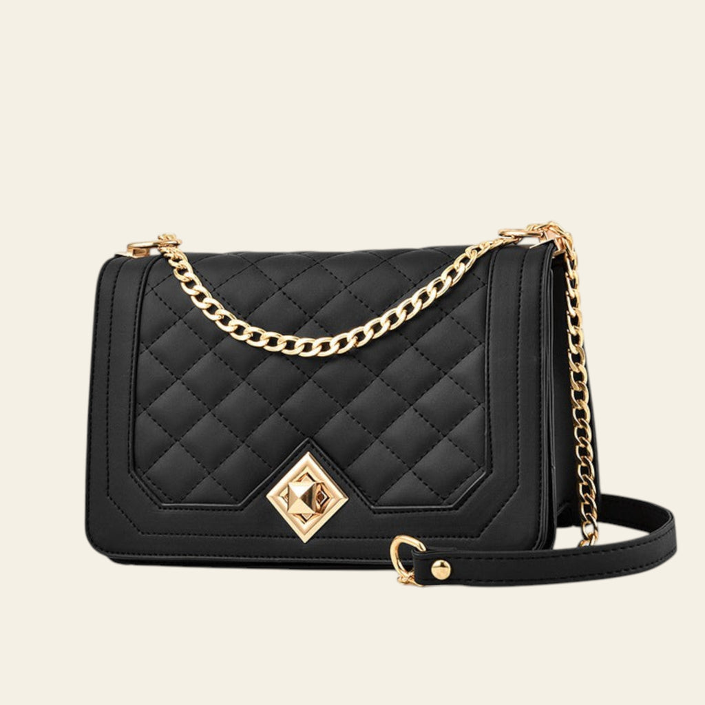 Black quilted handbag with gold chain strap and clasp on a white background