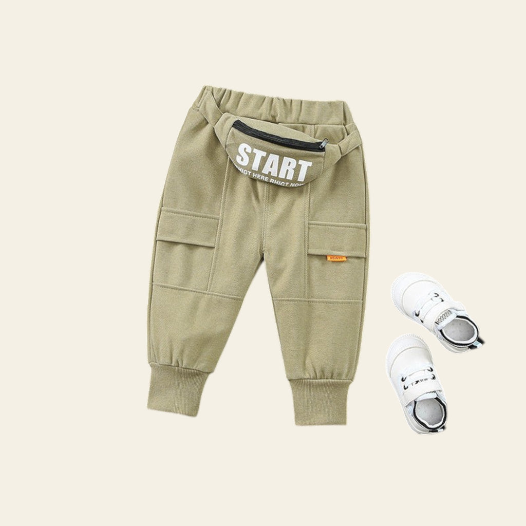 Green children's jogger pants with 'START' text on a gray textured surface.