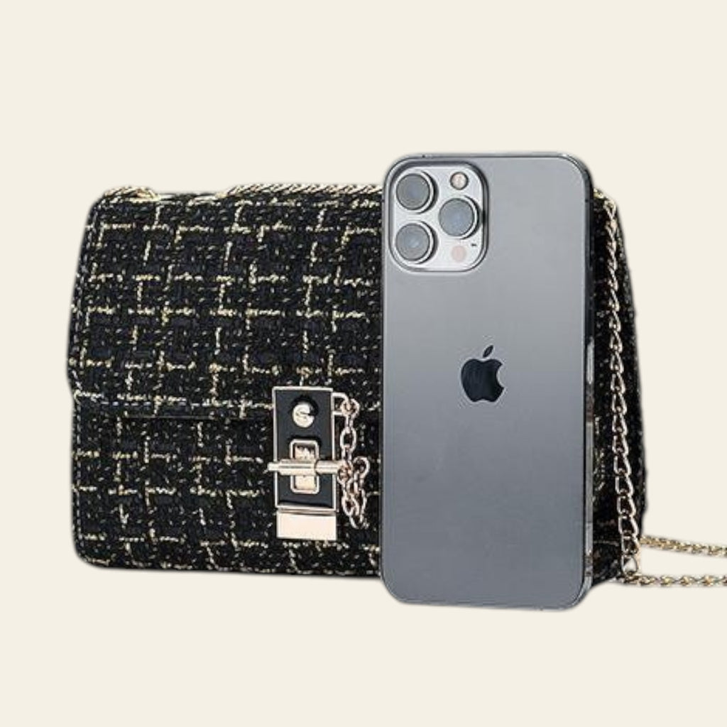 Black tweed handbag with gold chain and an iPhone 12 Pro Max on a light gray background