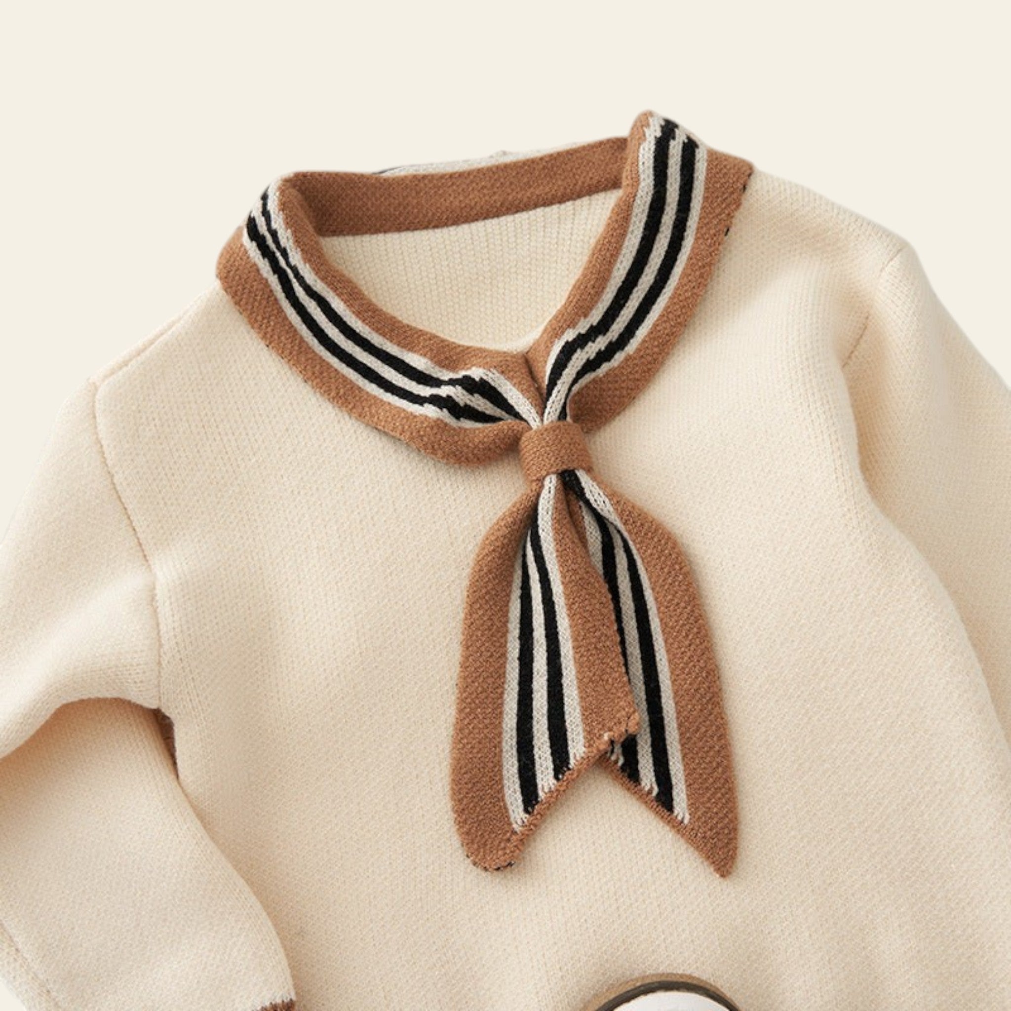 Close-up of a beige sweater with a brown striped scarf on a textured background