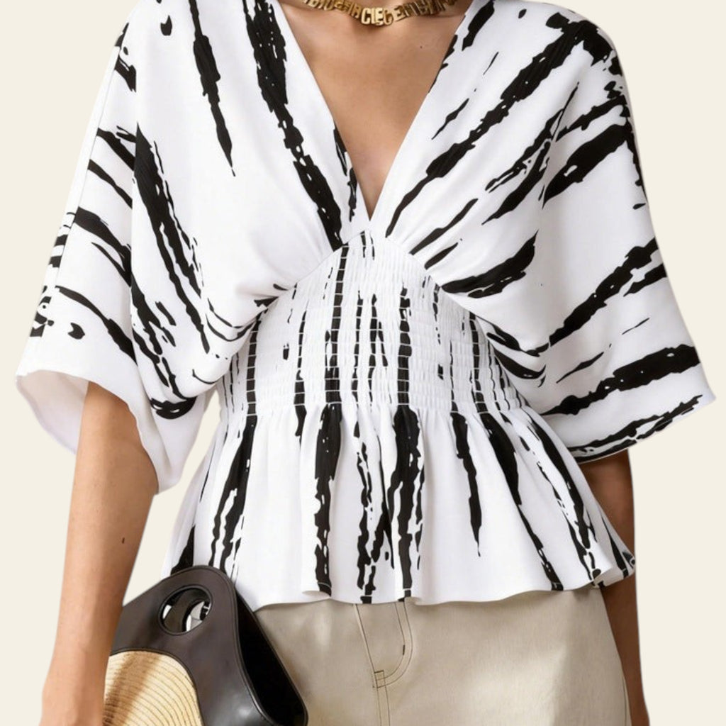 Woman wearing a white blouse with black abstract patterns on a beige background