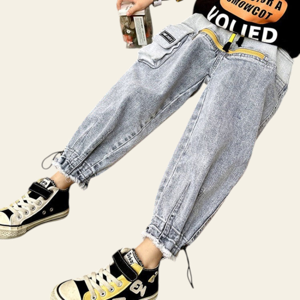 Person wearing gray jeans and black sneakers sitting on a wooden bench.