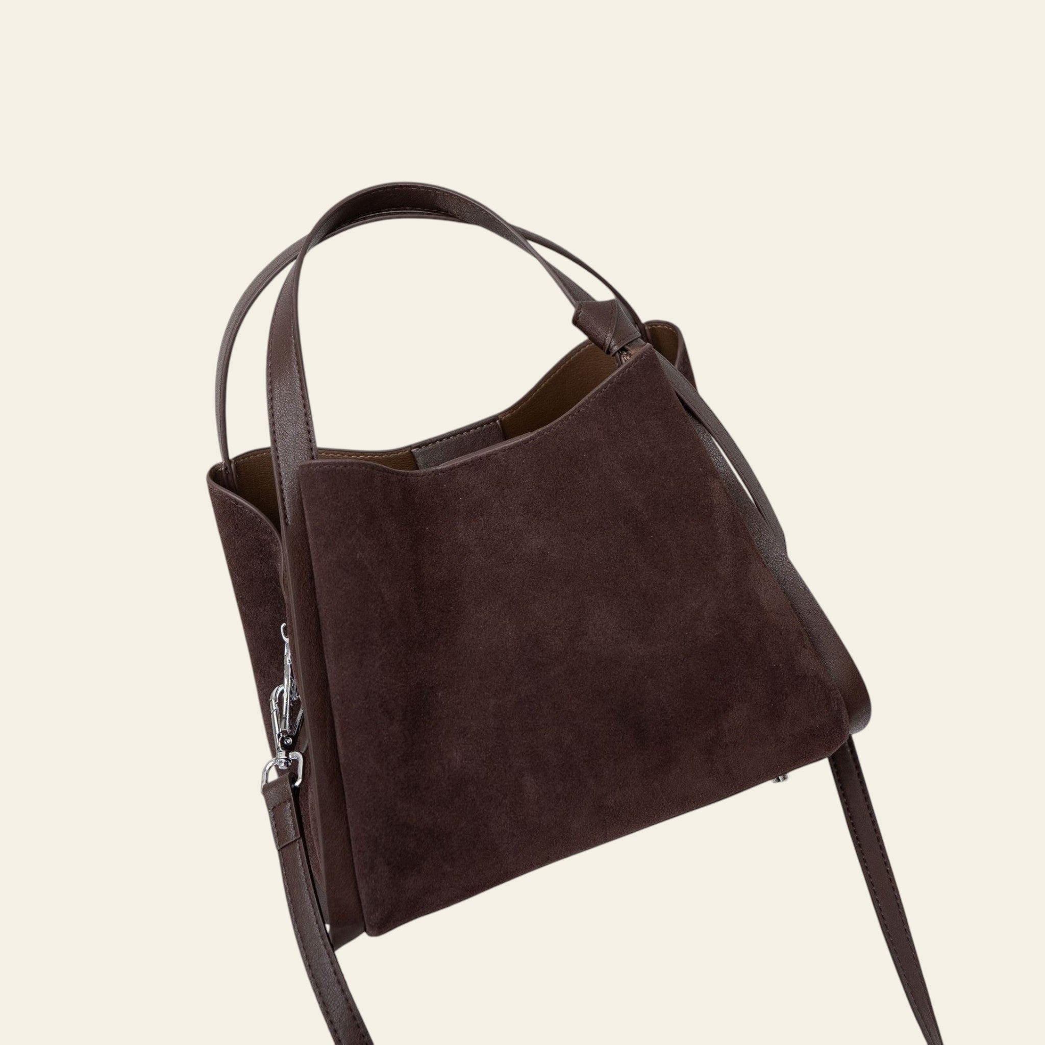 Brown leather handbag on a textured surface with a light background