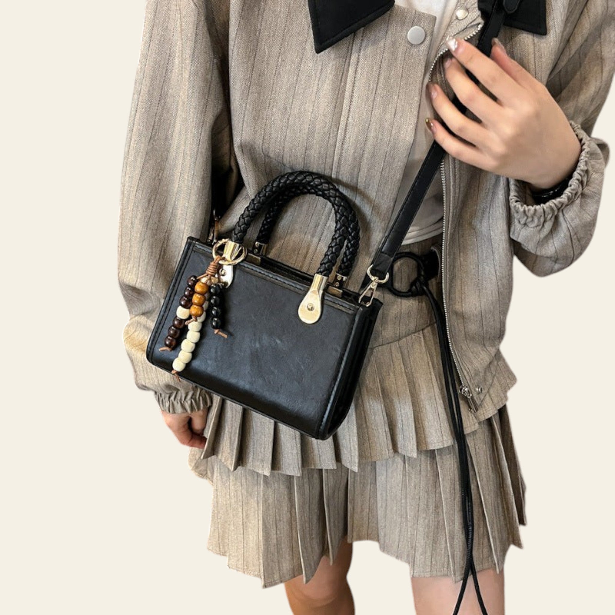 Person holding a black handbag with decorative elements in a room setting.