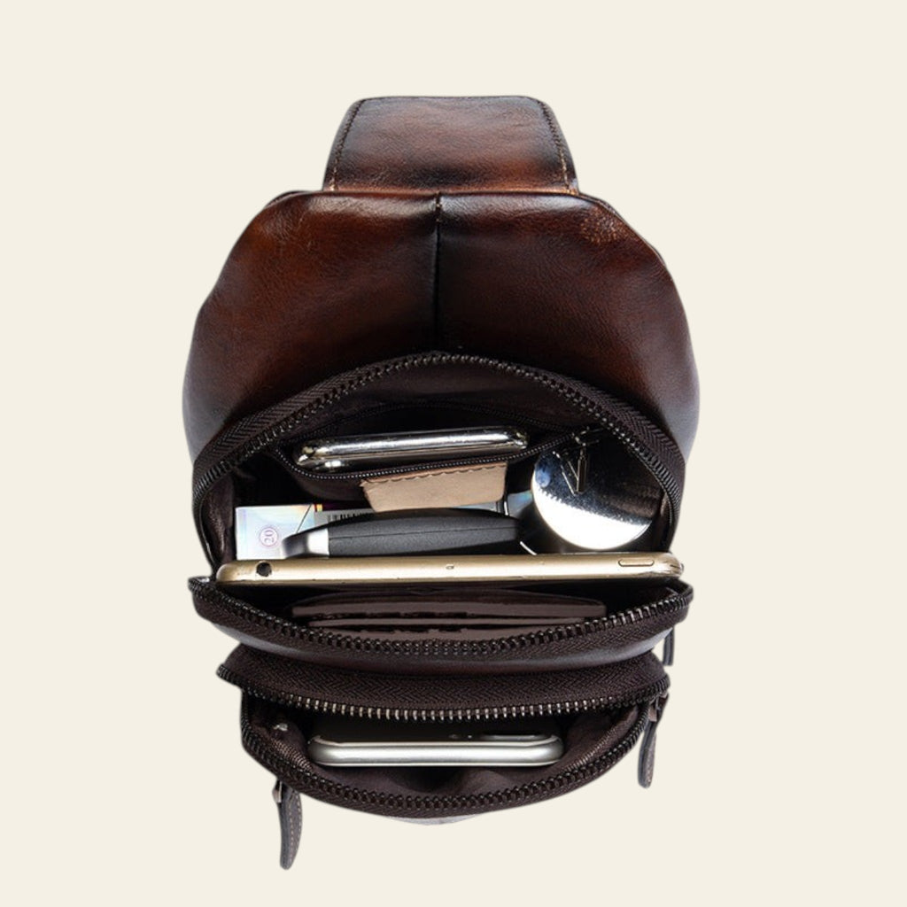 Brown leather multi-compartment pouch with various items on a white background