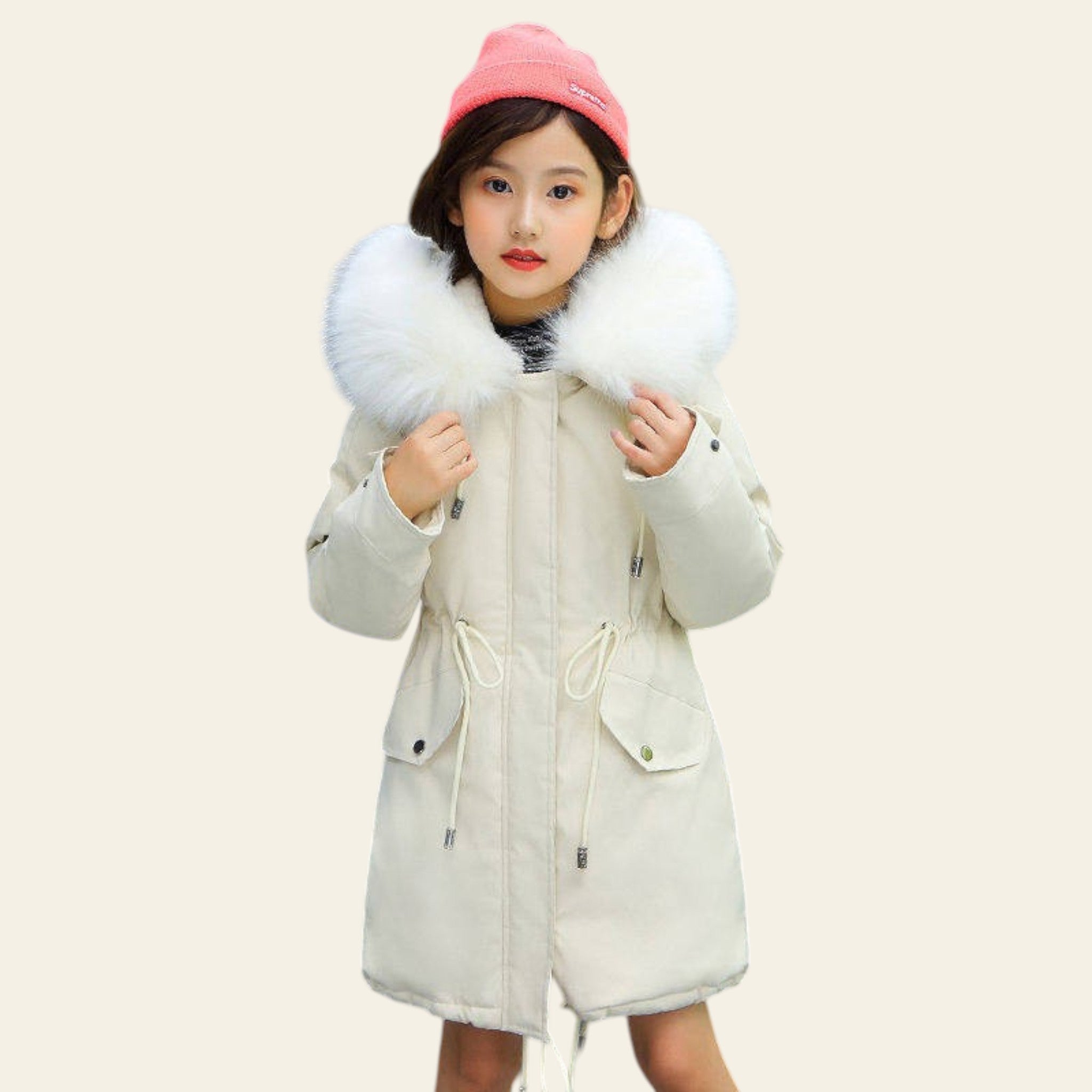 Child wearing a white coat with fur hood and pink beanie on a street.