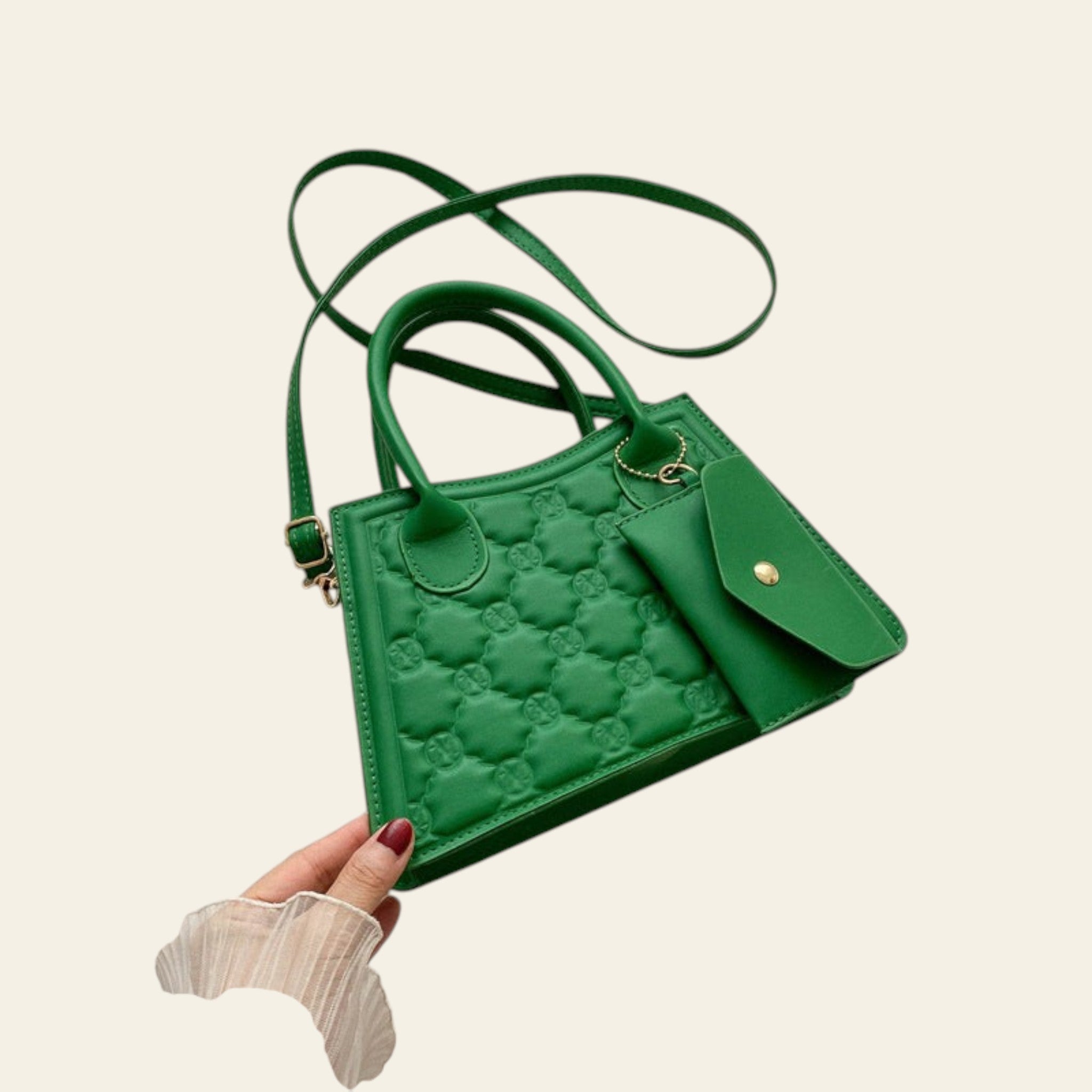 Green handbag with floral pattern held by a hand on a white background