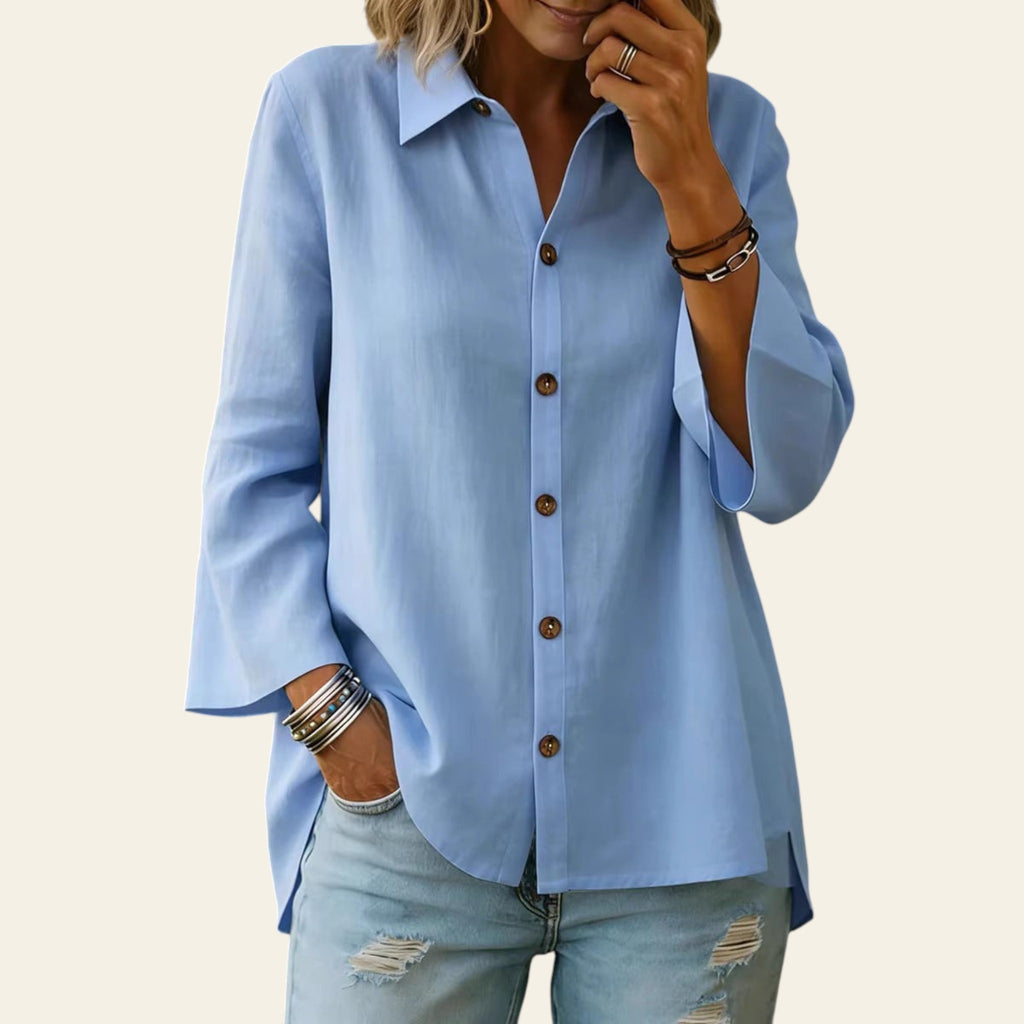 Person wearing a light blue button-up shirt and distressed jeans with a blurred background