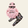 Pink hoodie with 'Mama's Bestie' text and camouflage pants on a wooden surface.