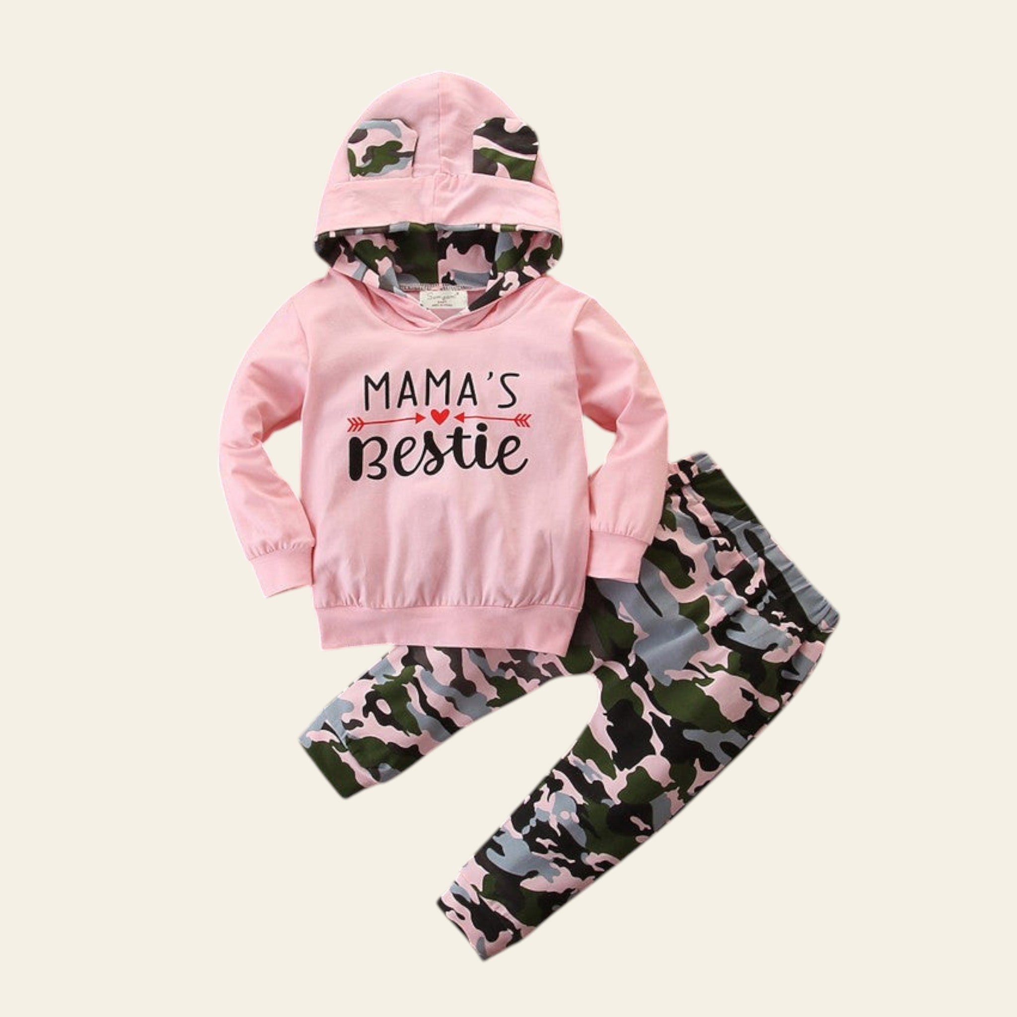 Pink hoodie with 'Mama's Bestie' text and camouflage pants on a wooden surface.