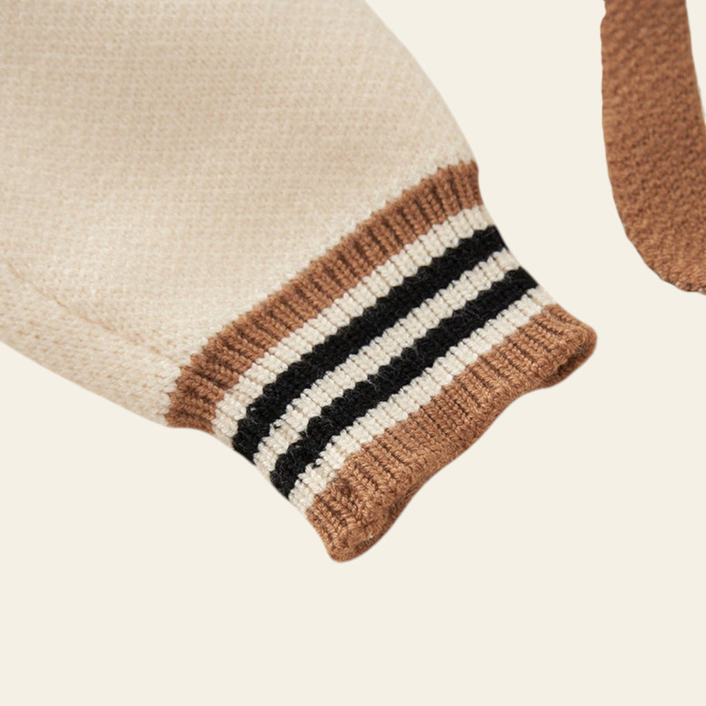 Knitted wristband with brown, black, and white stripes on a beige background