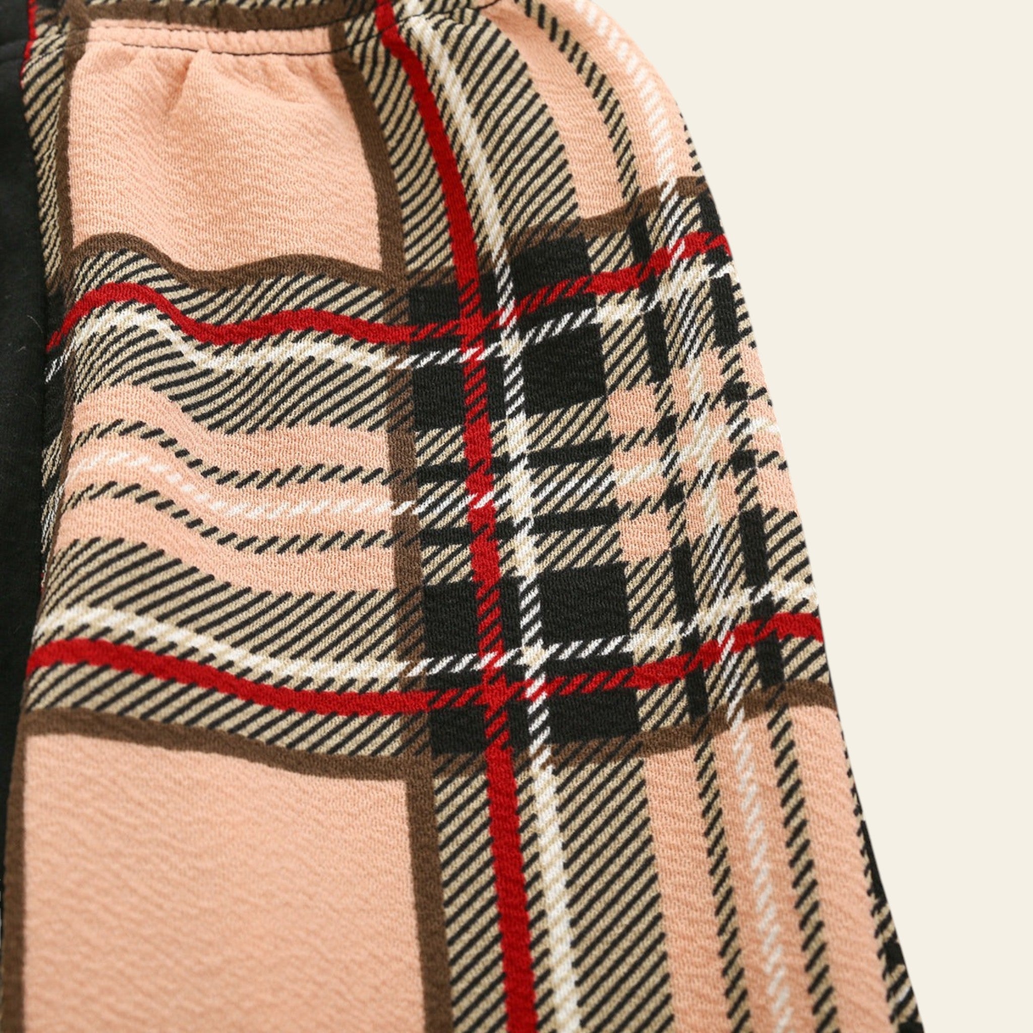 Plaid patterned fabric with pink, black, and red colors on a wooden surface