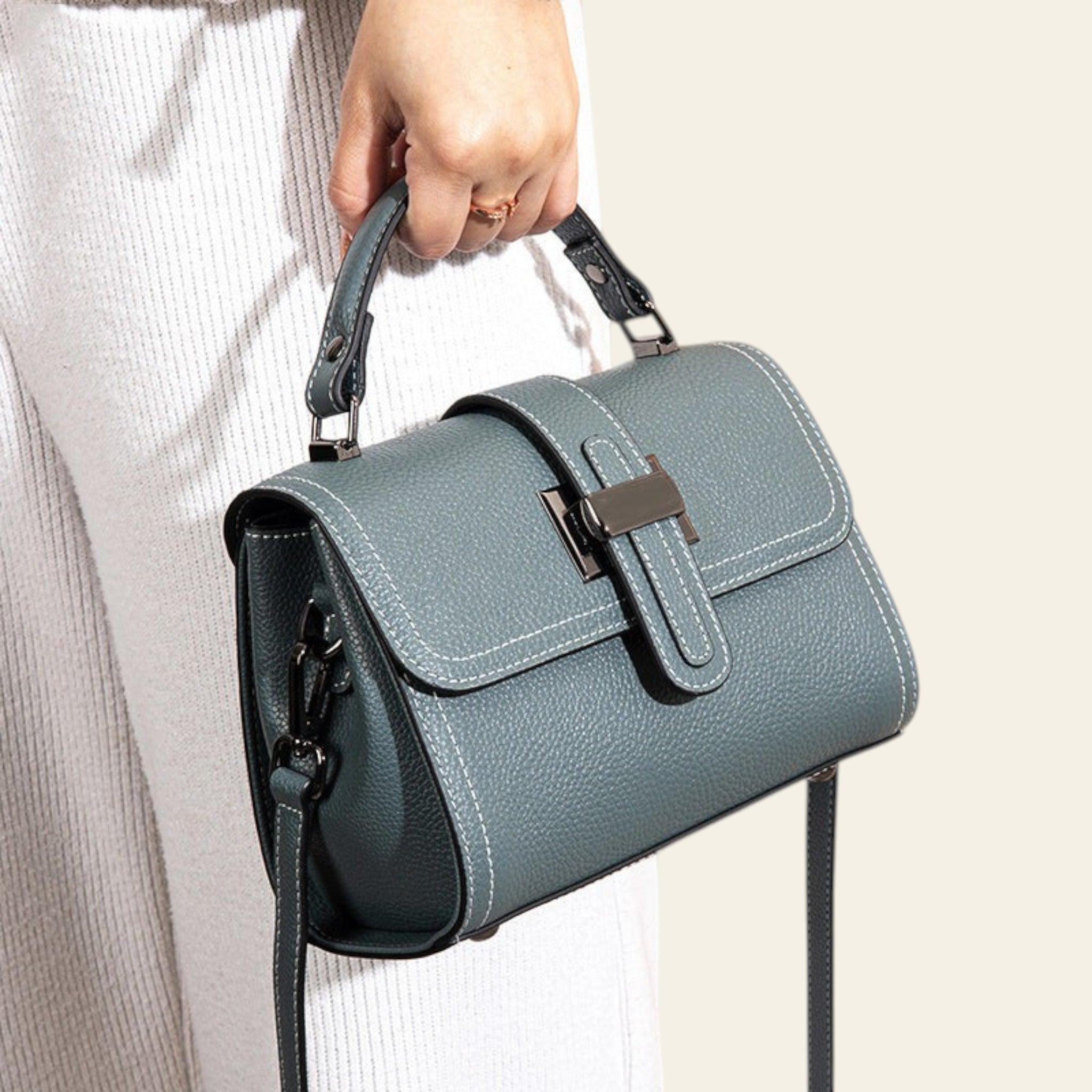 Blue handbag held by a person against a neutral background