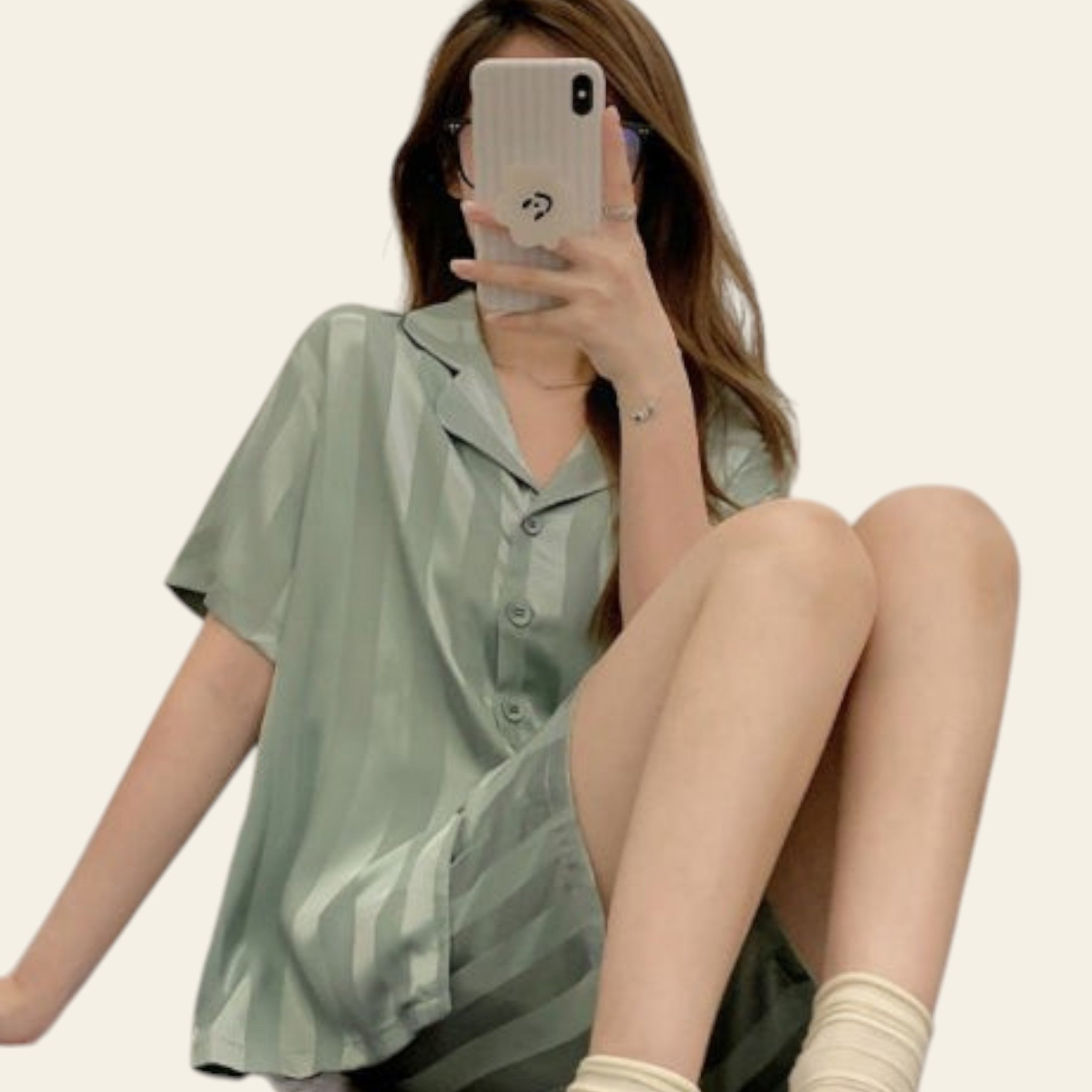 Person wearing a light green shirt sitting on a bed.