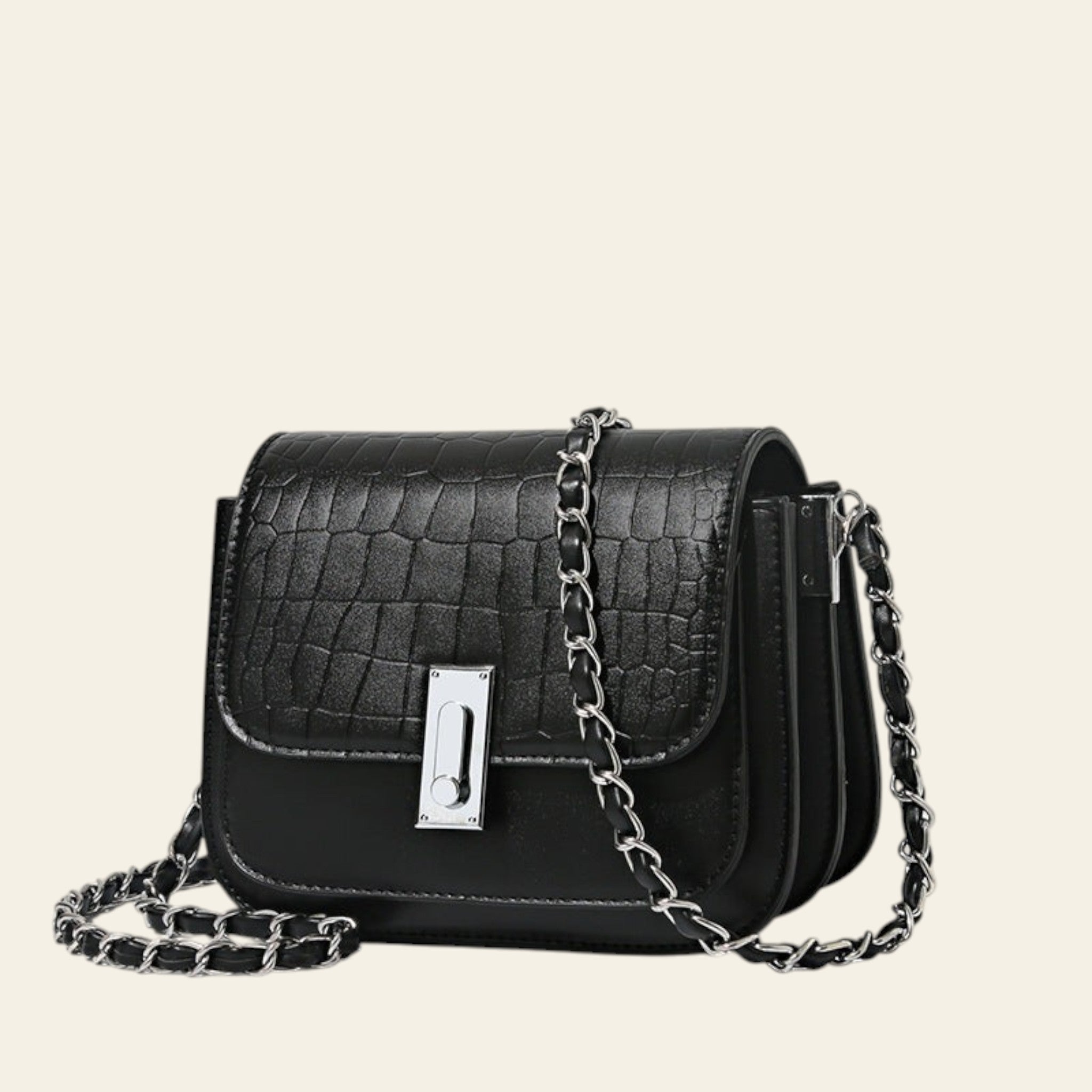 Black crocodile-patterned handbag with a chain strap on a beige background