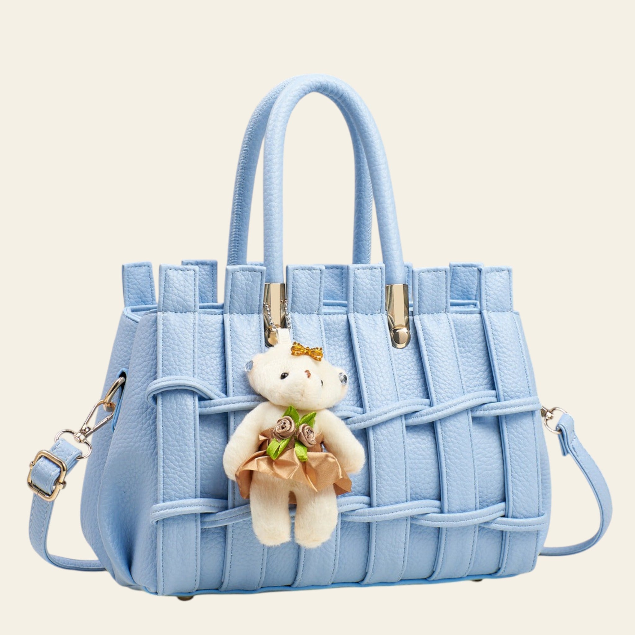 Light blue handbag with a teddy bear keychain on a gray background