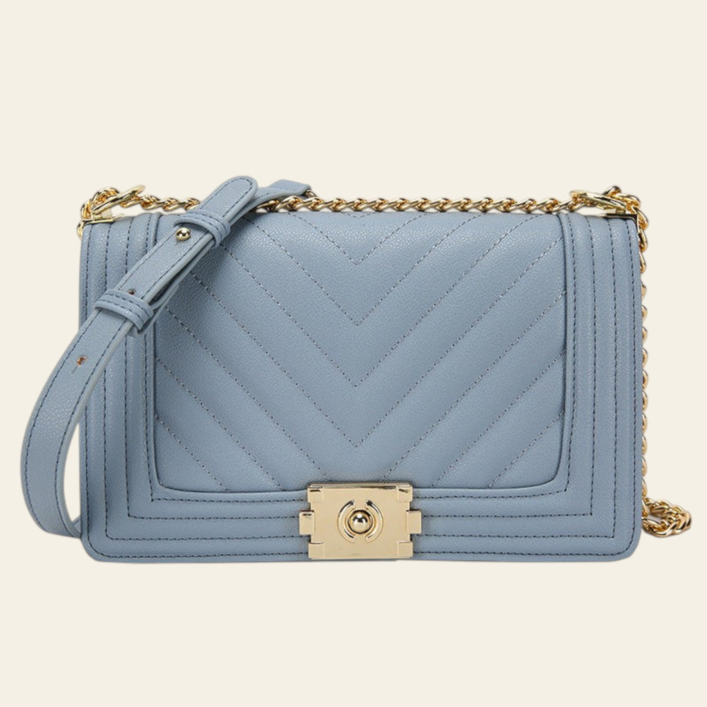 Blue handbag with gold chain and clasp on a white background